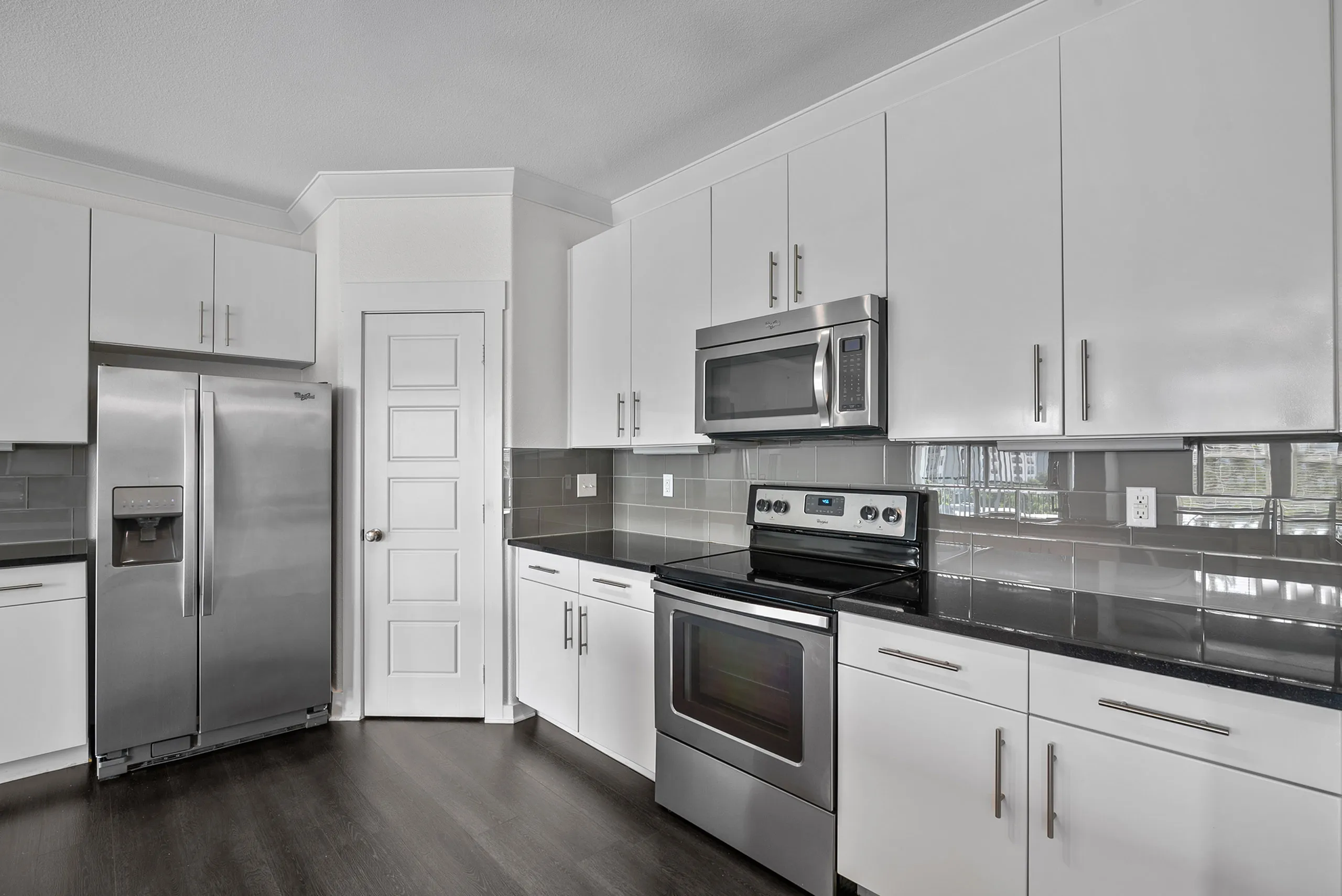 Sleek modern kitchen with stainless steel appliances, glossy countertops, and ample white cabinetry.