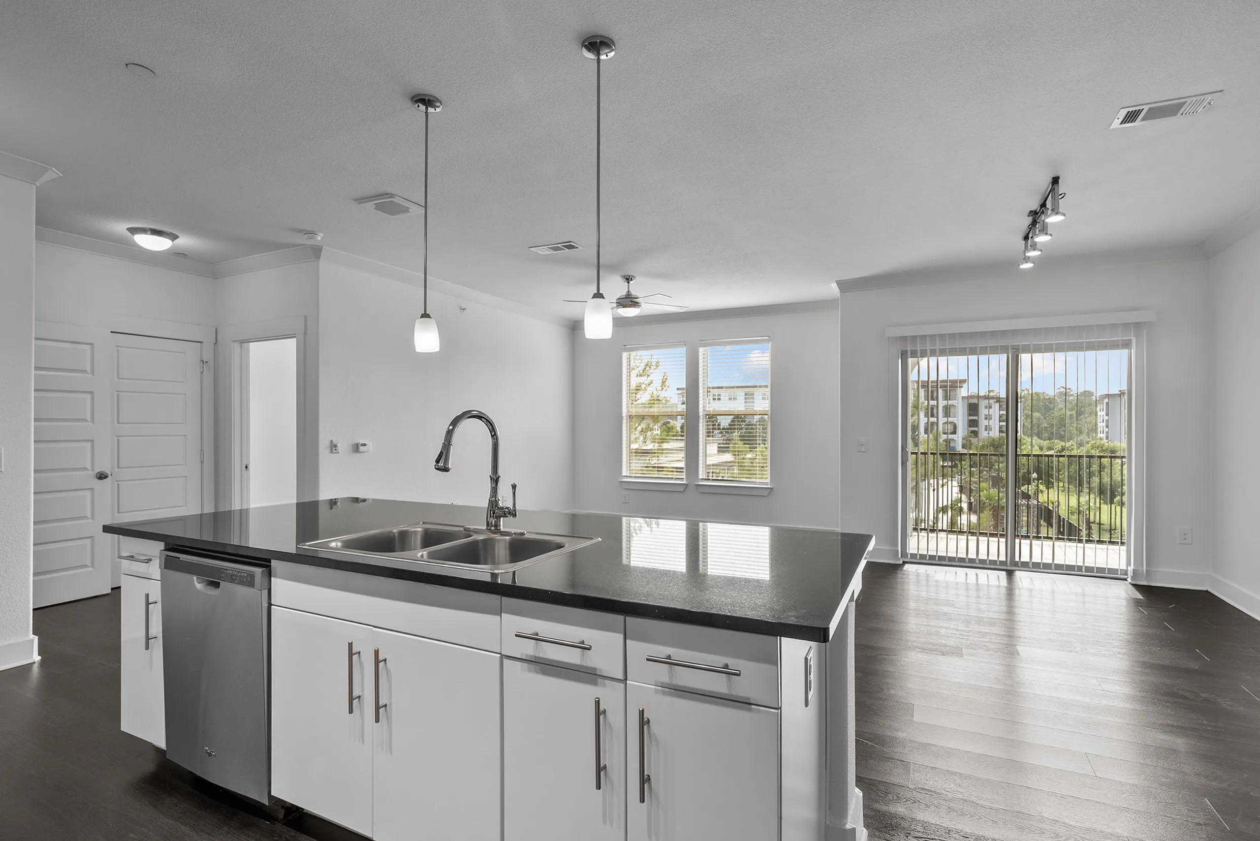 Modern open-concept kitchen and living area with sleek countertops, pendant lighting, and large windows overlooking a scenic view.