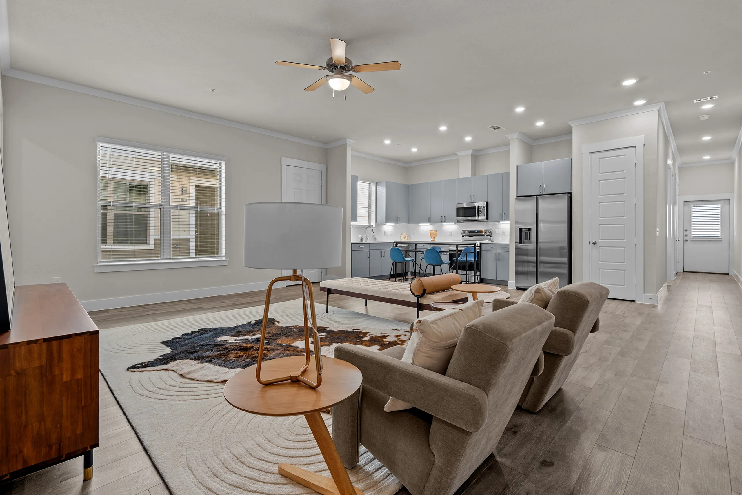 Modern open-concept living room with elegant furnishings, stylish kitchen, and natural light streaming in through large windows.