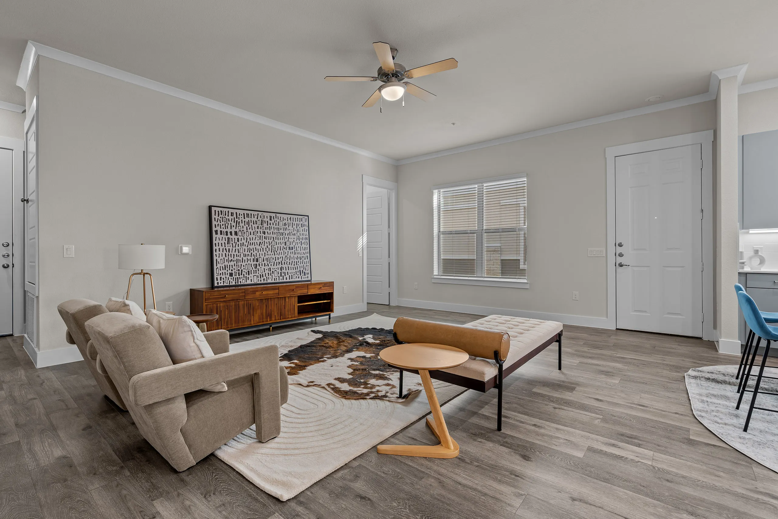 Inviting living room with modern decor, featuring a cozy beige sofa, stylish wooden furniture, and large windows for natural light.