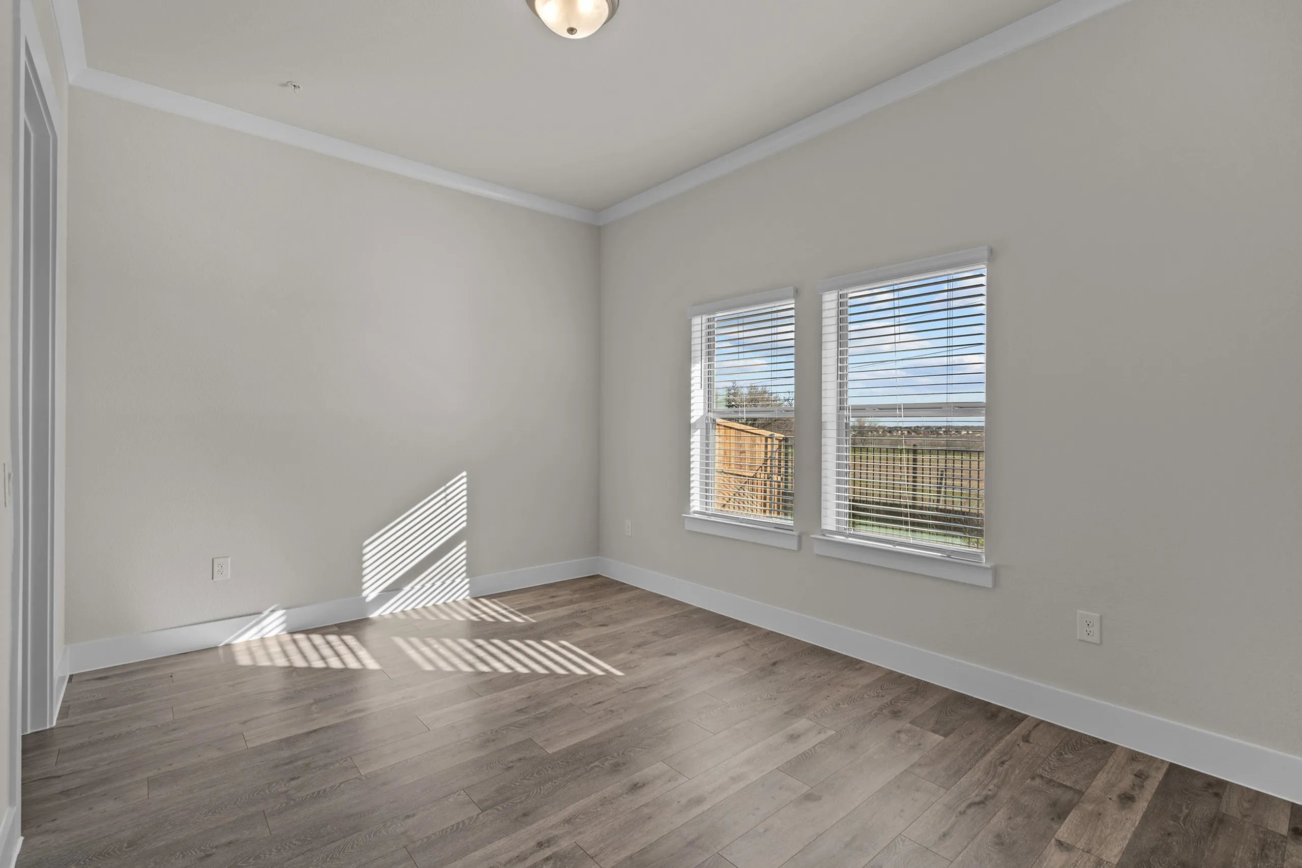 Bright room with large windows and elegant wood flooring, offering a tranquil view of the outdoor space and abundant natural light.