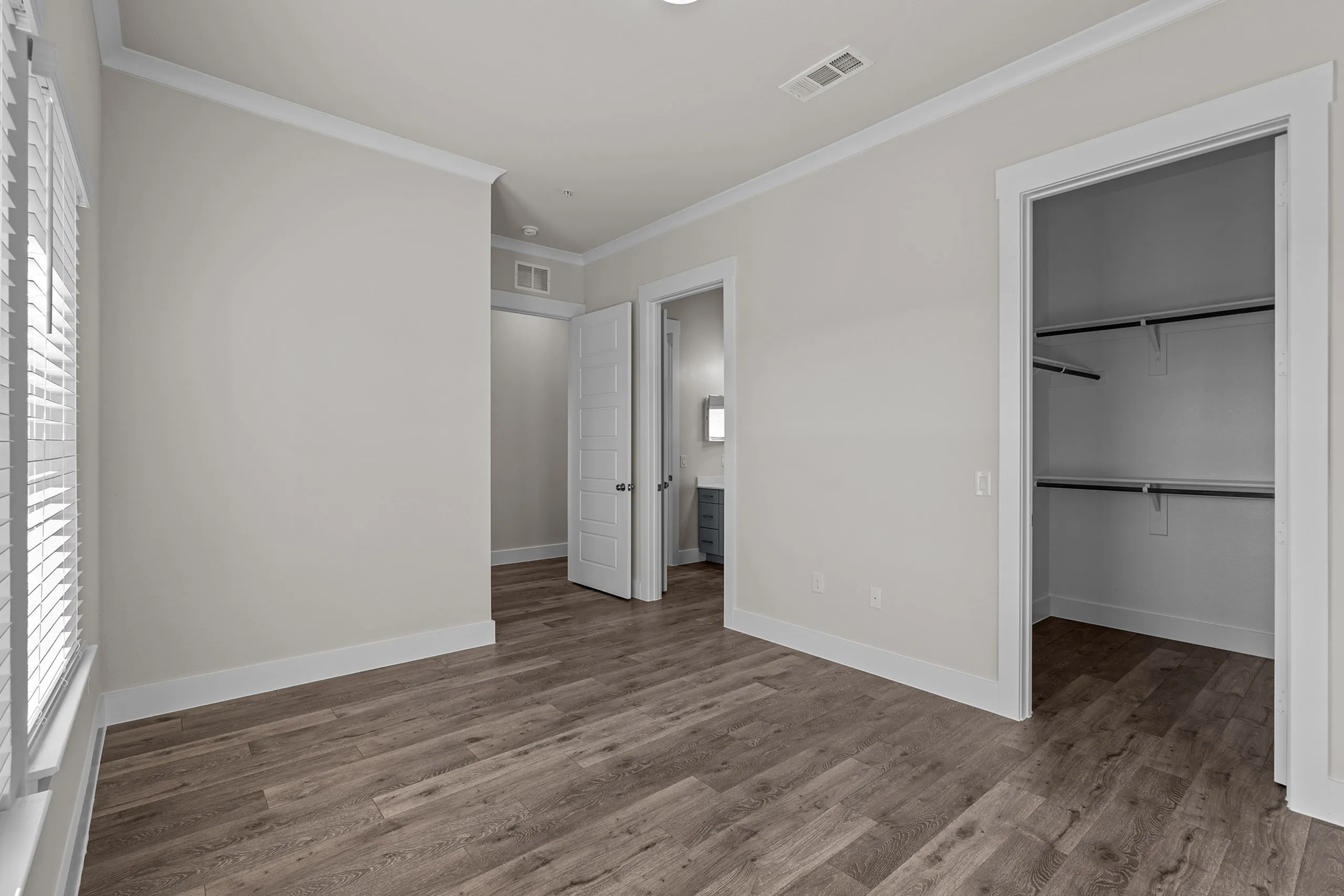 Bright apartment room with elegant hardwood flooring, spacious walk-in closet, and ample natural light from large windows.
