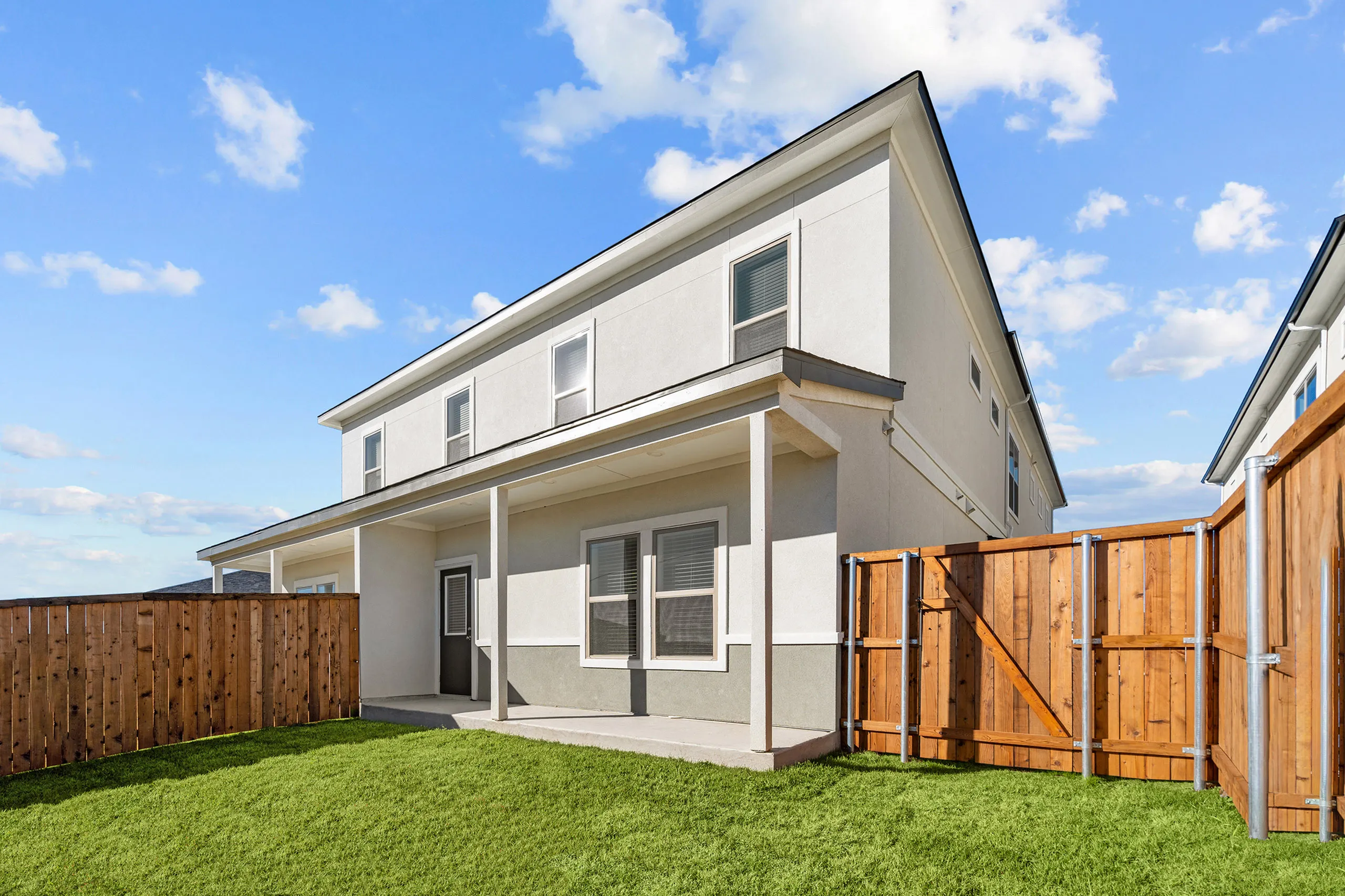 Charming two-story house exterior with a spacious fenced backyard, perfect for family living and outdoor enjoyment.