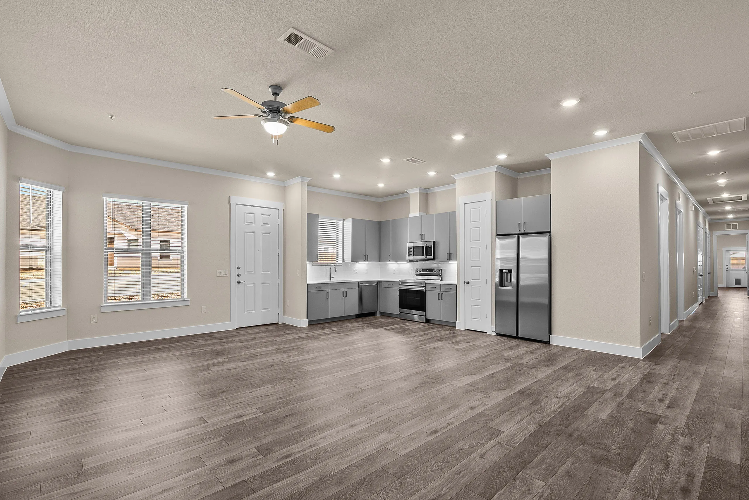 Modern open-concept kitchen and living area with sleek gray cabinetry, stainless steel appliances, and elegant hardwood floors.
