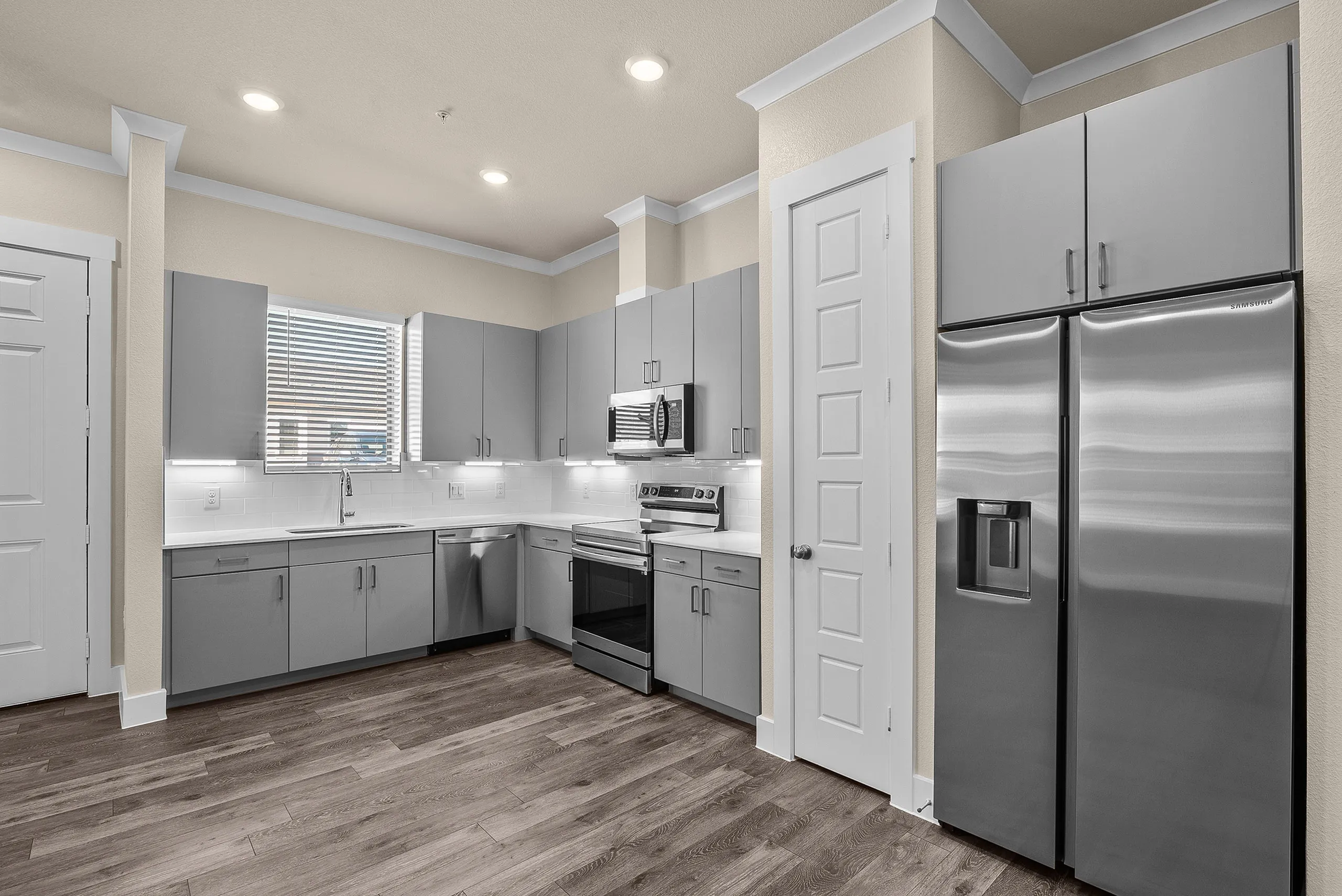Modern kitchen with sleek grey cabinetry, stainless steel appliances, and elegant wood flooring.