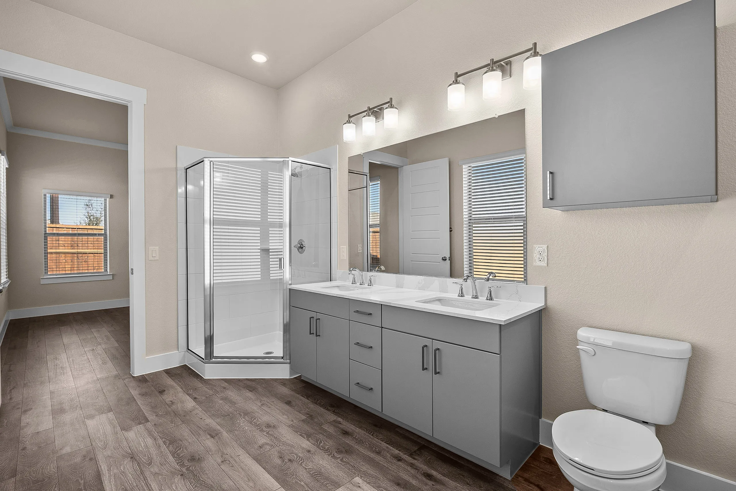 Modern bathroom featuring a dual-sink vanity, spacious shower, and elegant lighting fixtures.