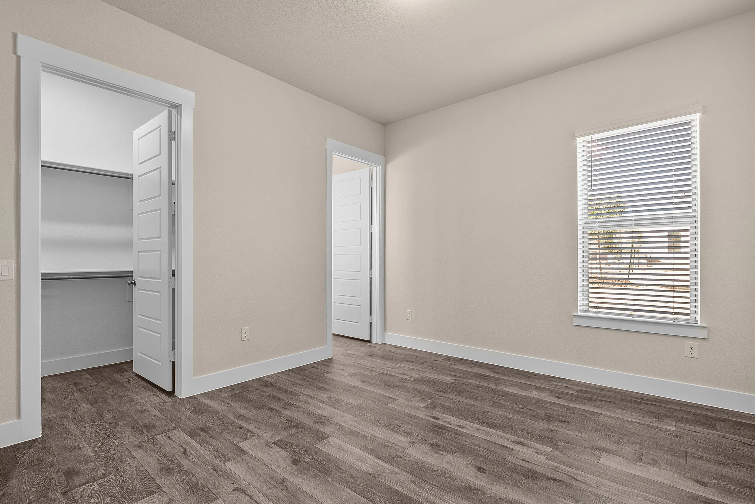 Bright and inviting bedroom with sleek hardwood floors, a spacious closet, and sunlit window.