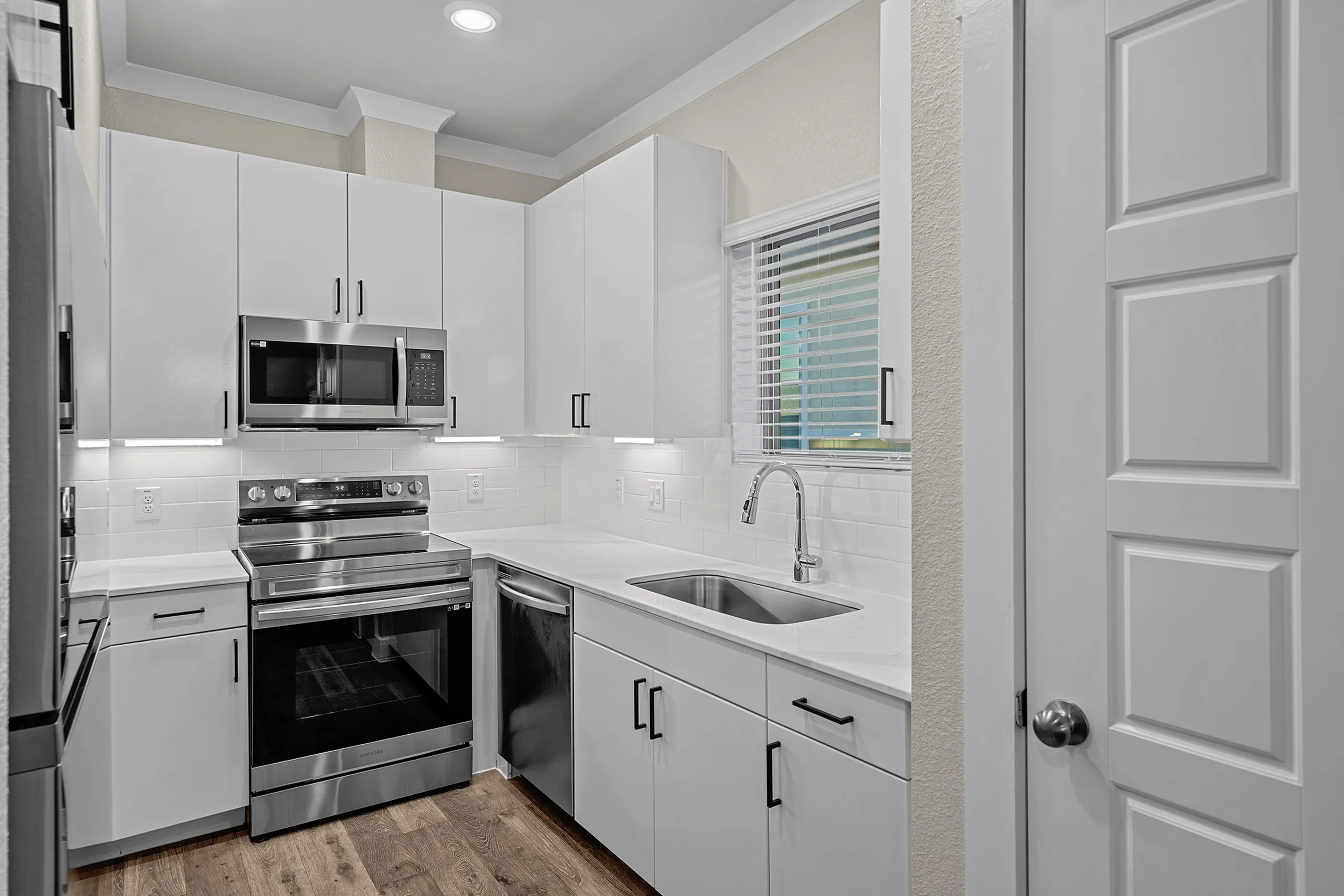 Modern kitchen featuring sleek white cabinets, stainless steel appliances, and elegant hardwood floors.