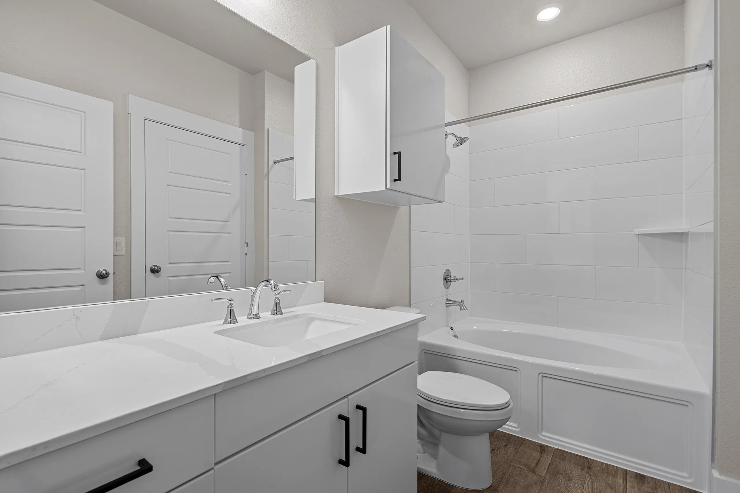 Modern bathroom with elegant white cabinetry, a sleek countertop, and a spacious bathtub, complemented by stylish fixtures and warm lighting.
