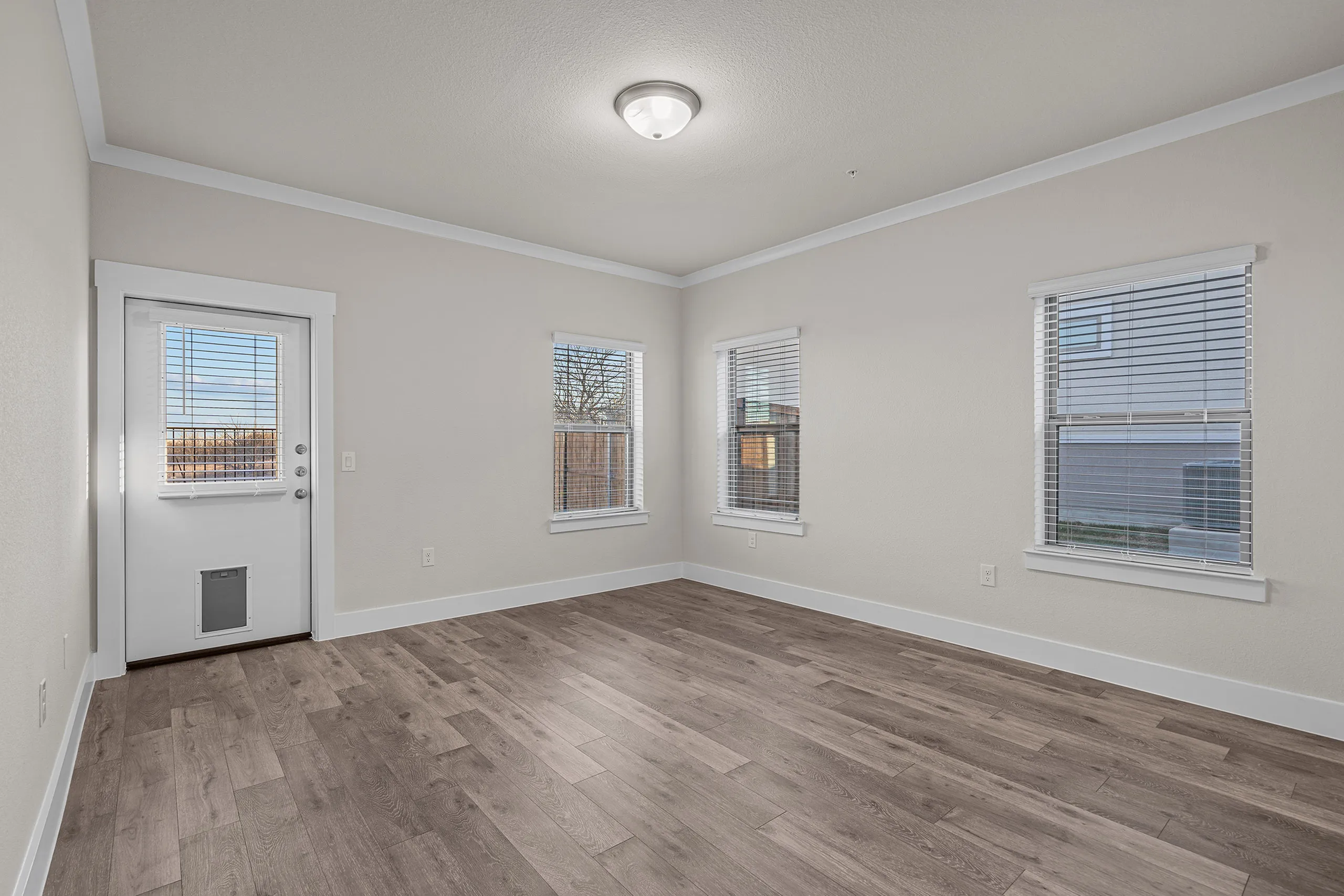 Bright and spacious room with elegant wood flooring and large windows for natural light.
