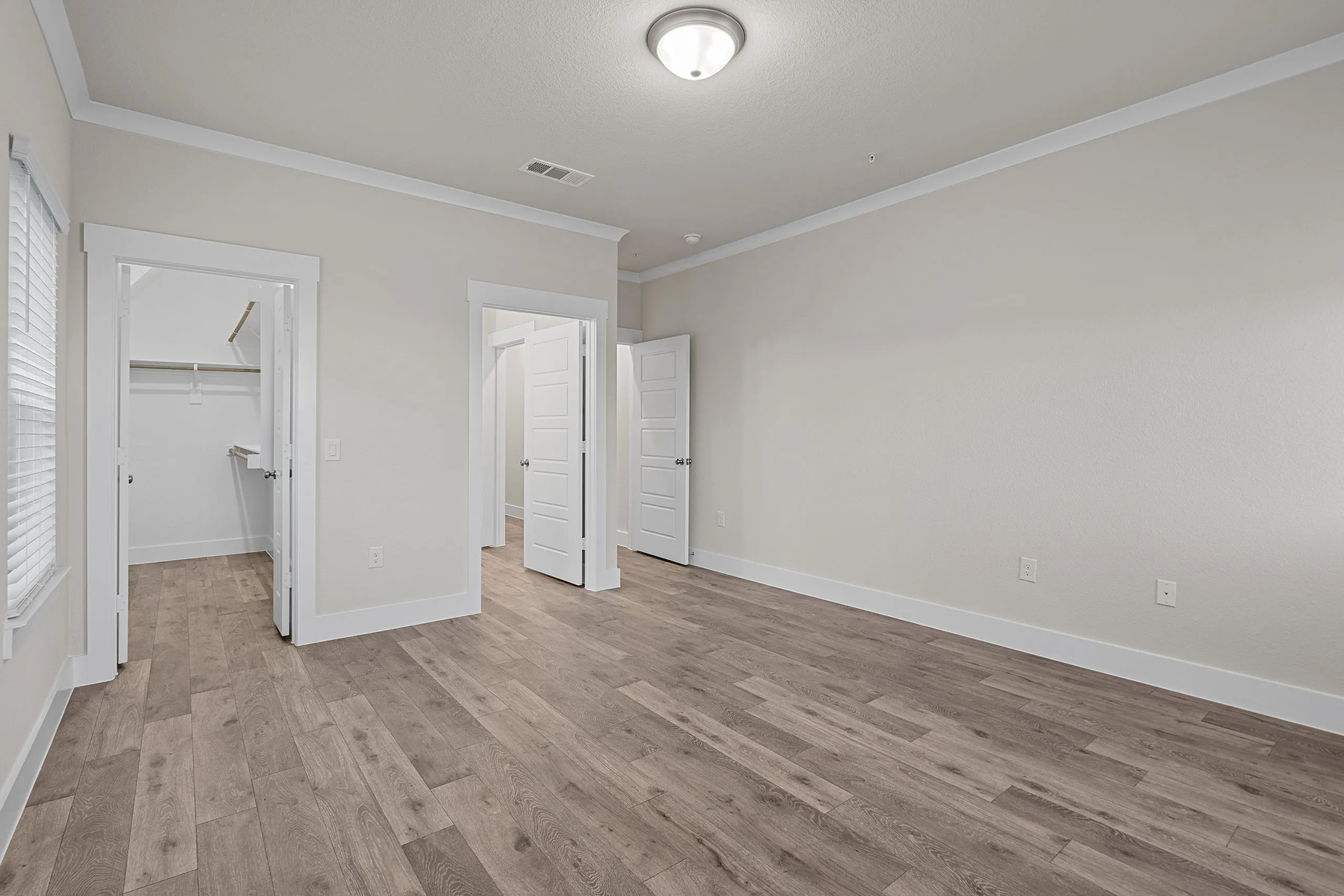 Inviting empty bedroom with elegant wood flooring, neutral walls, and ample closet space.