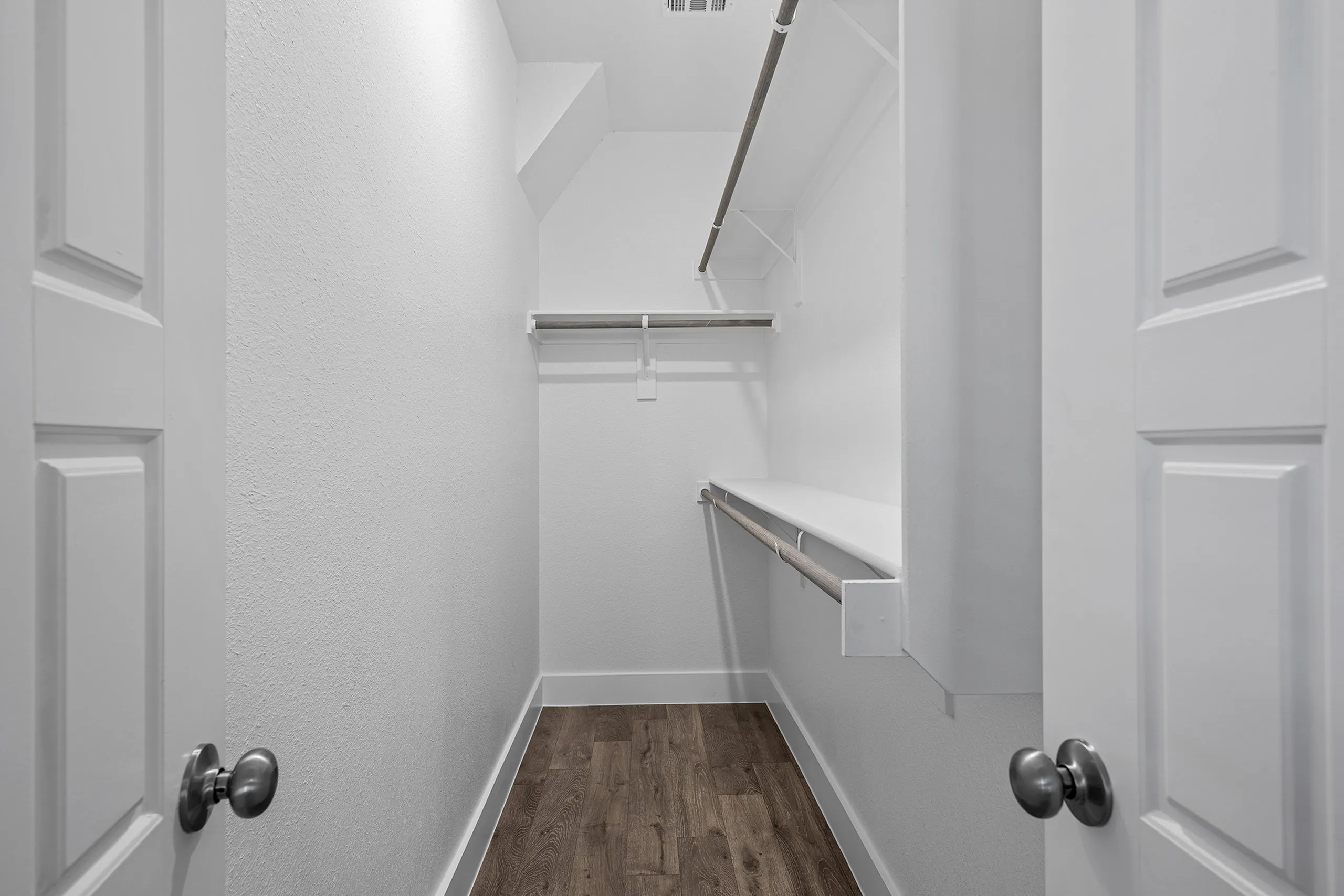 Spacious walk-in closet with wooden flooring and ample hanging space, perfect for organizing your wardrobe elegantly.