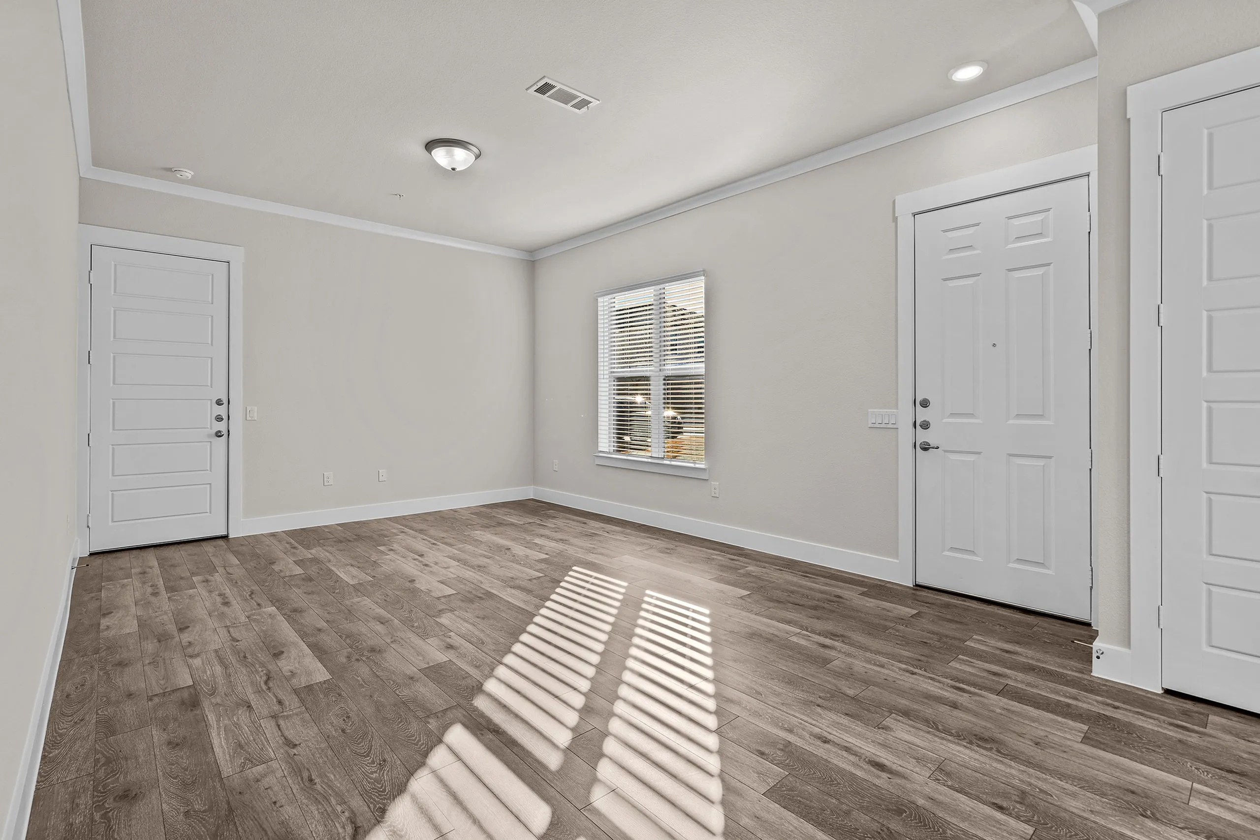Bright, inviting entryway featuring elegant wood flooring and modern doors, accented by natural light from the window.