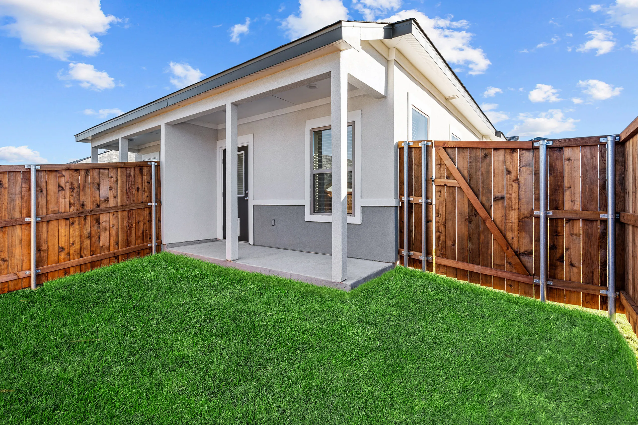 Charming fenced backyard with vibrant green lawn and modern patio, perfect for relaxation and outdoor entertainment.