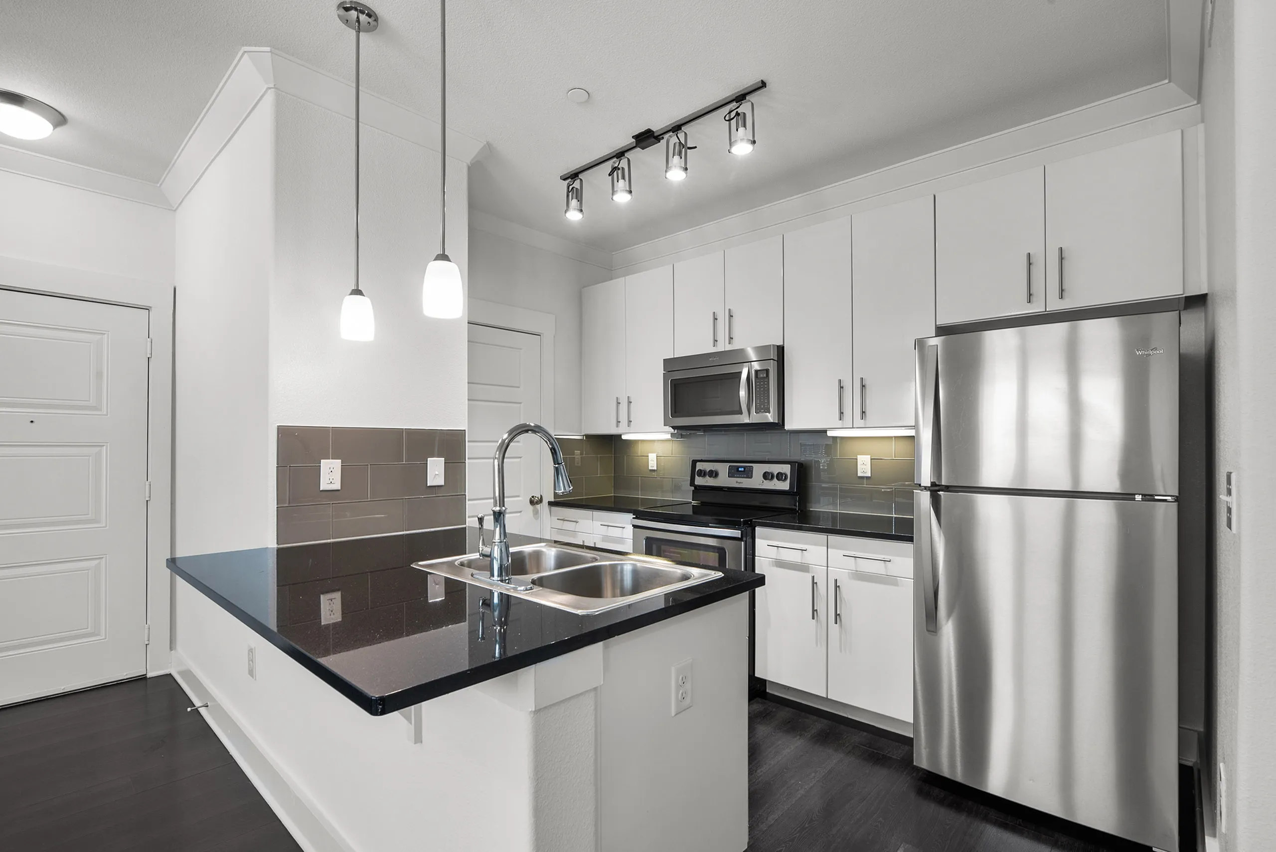 Modern kitchen with sleek white cabinetry, stainless steel appliances, and elegant pendant lighting.