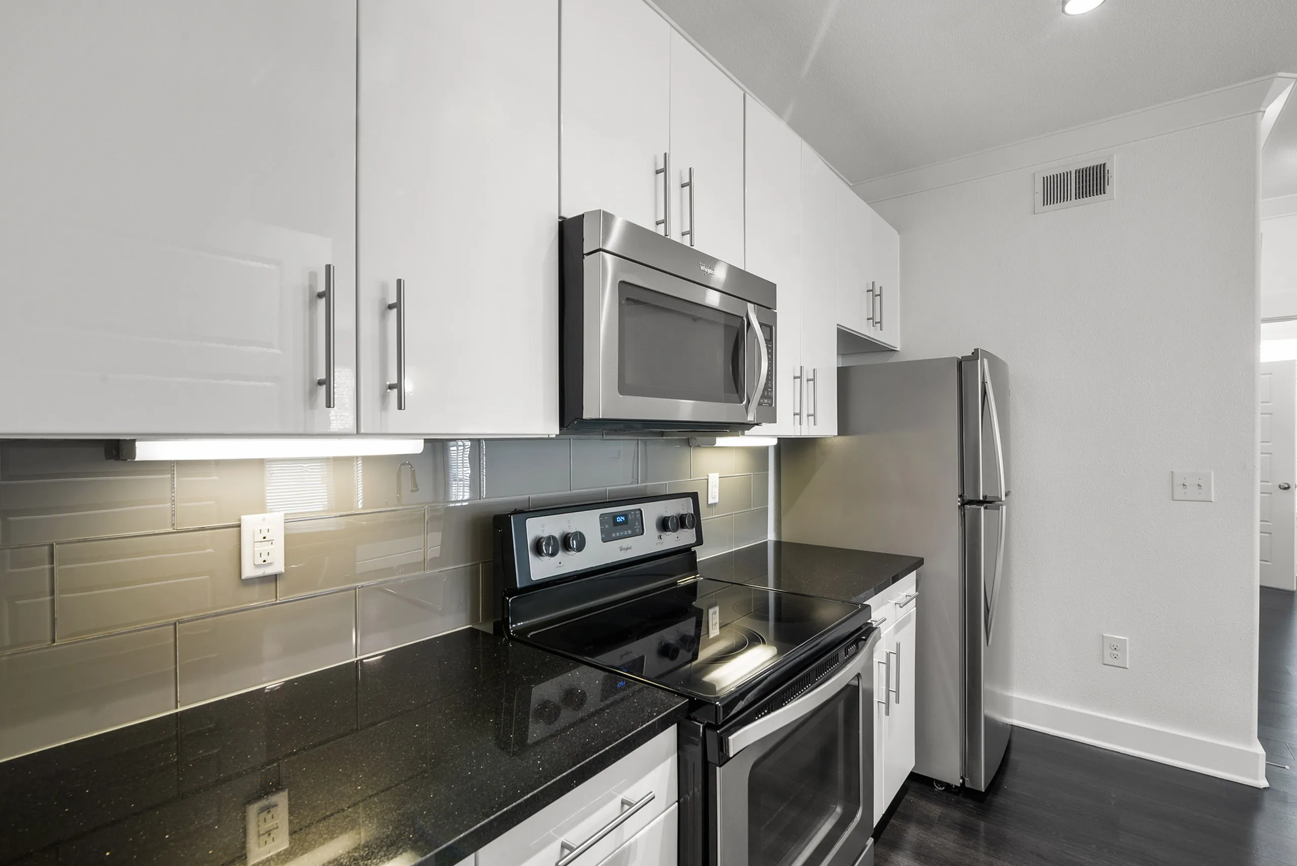 Modern kitchen with sleek stainless steel appliances, glossy white cabinetry, and a stylish backsplash.