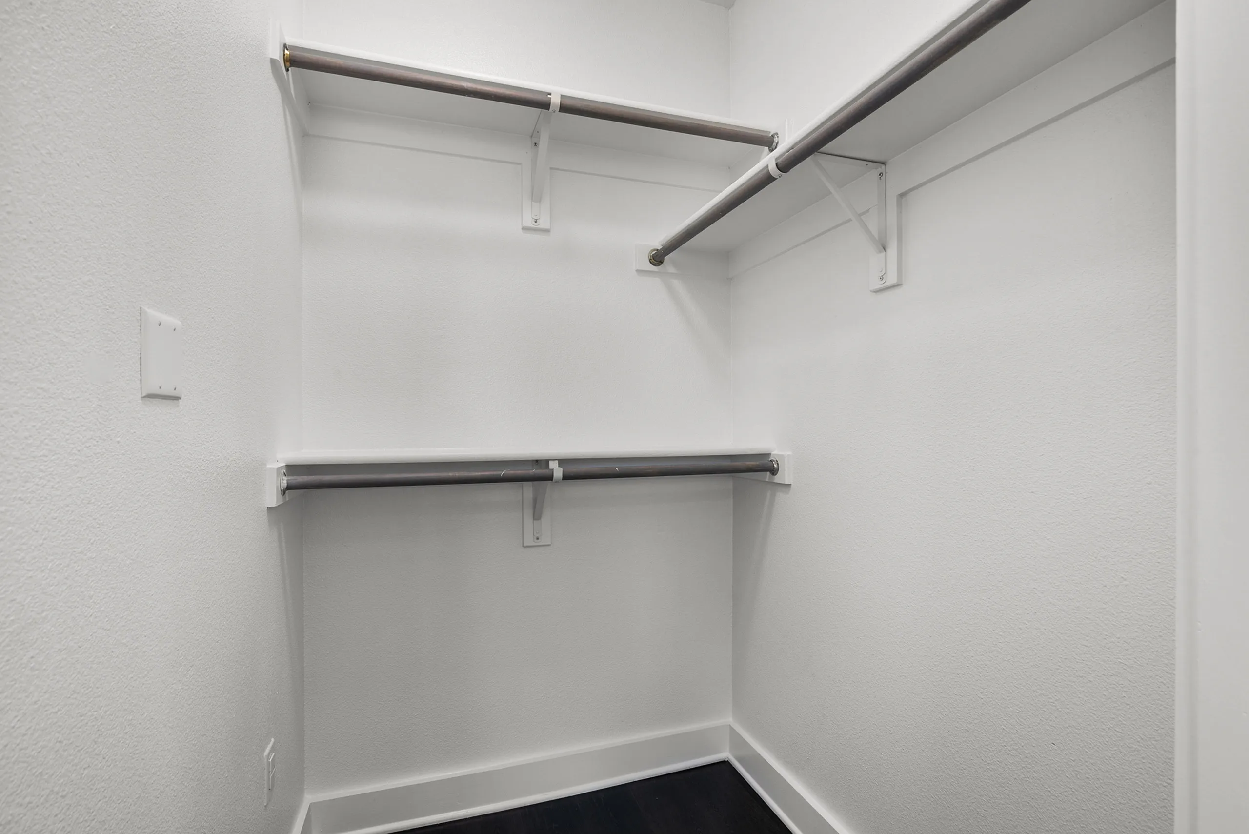 Spacious walk-in closet with clean white walls, sturdy double hanging rods, and modern shelving for optimal storage organization.