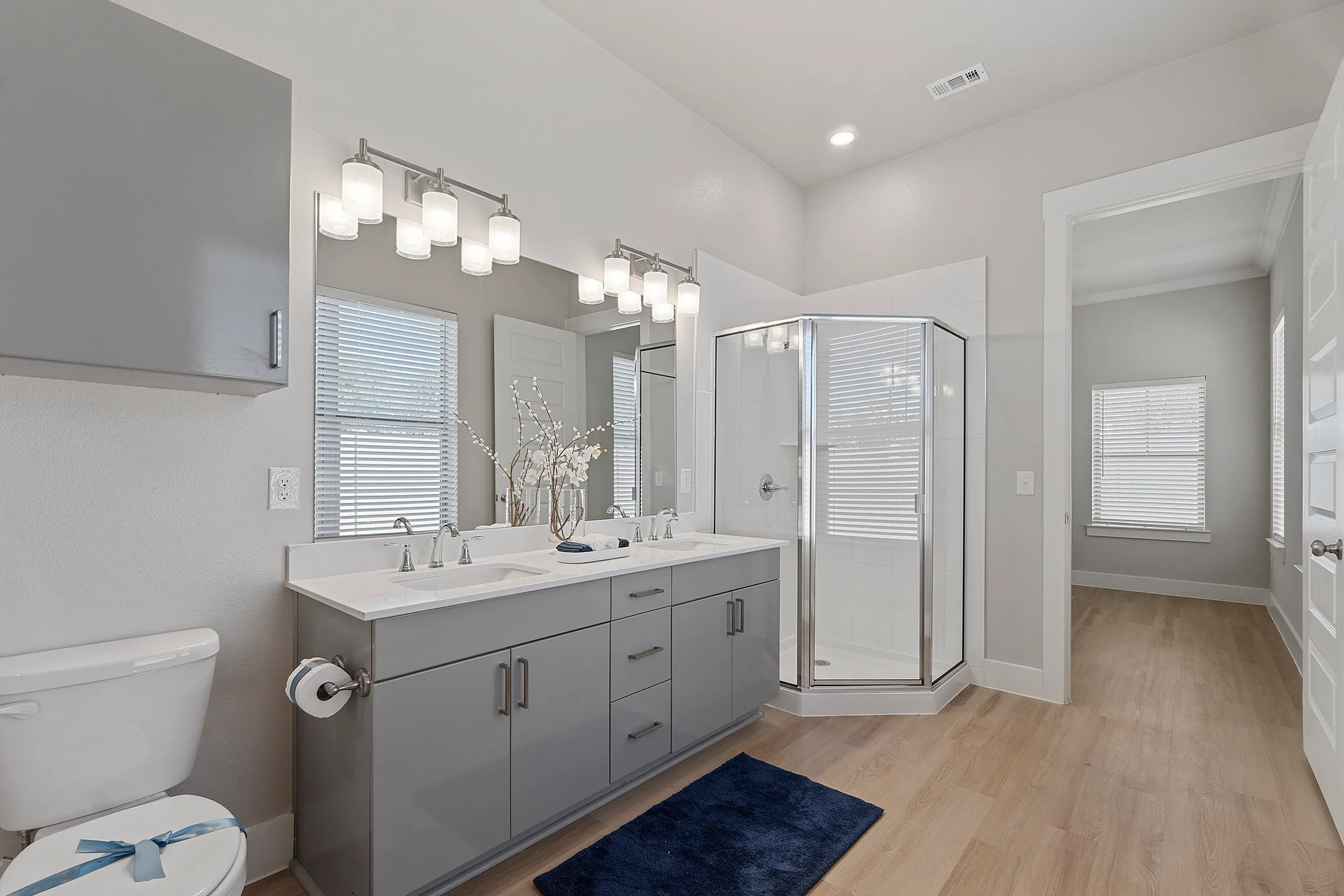 Modern bathroom featuring a sleek double vanity, chic lighting, and a spacious glass shower.