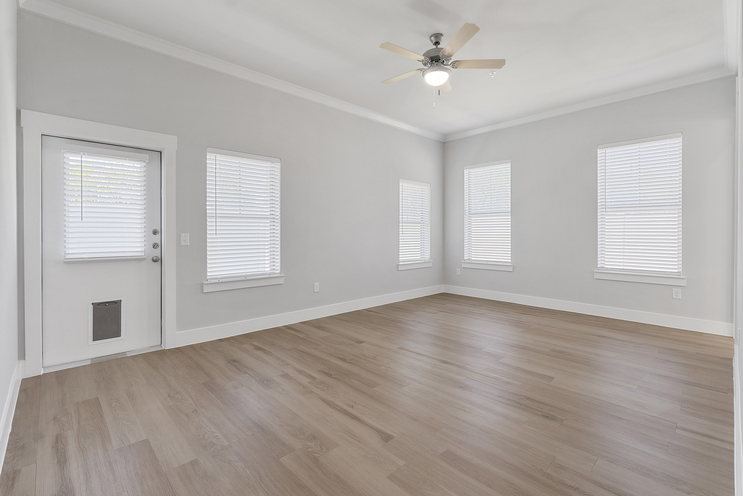 Bright and spacious living area with modern wood flooring and large windows, perfect for natural light.