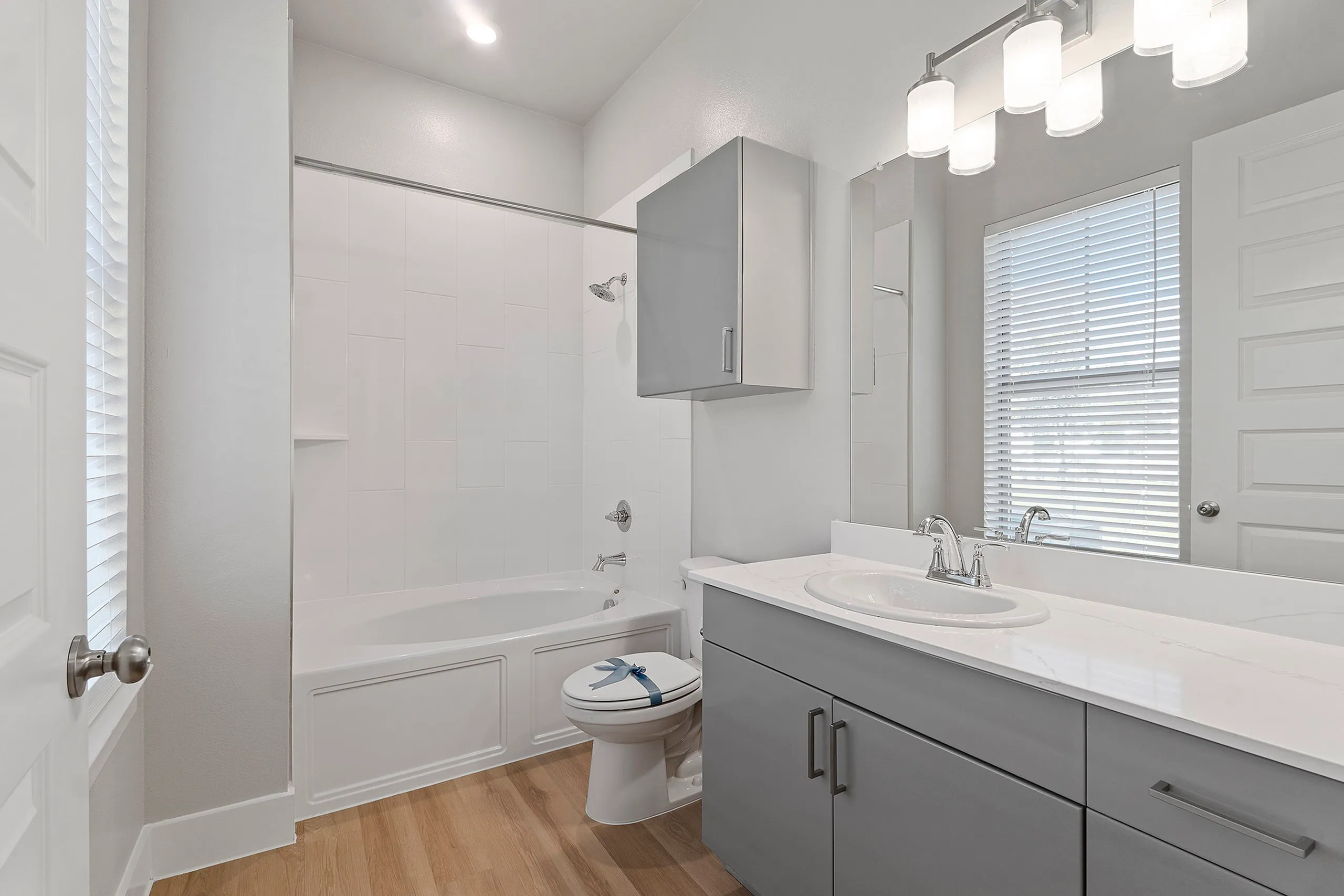 Contemporary bathroom design with sleek gray cabinetry, elegant lighting, and a pristine white bathtub.