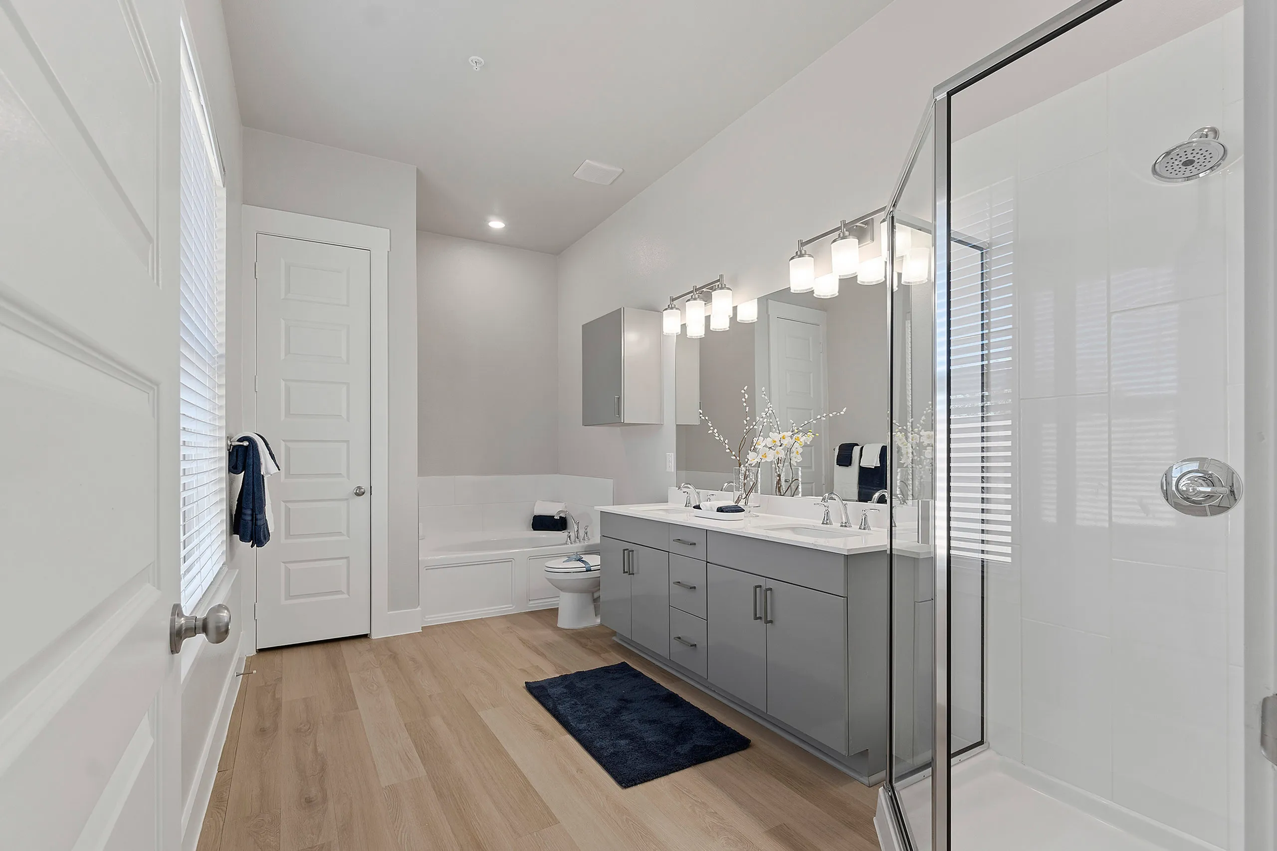 Elegant bathroom featuring dual sinks, a modern glass shower, and a luxurious bathtub with soft lighting.