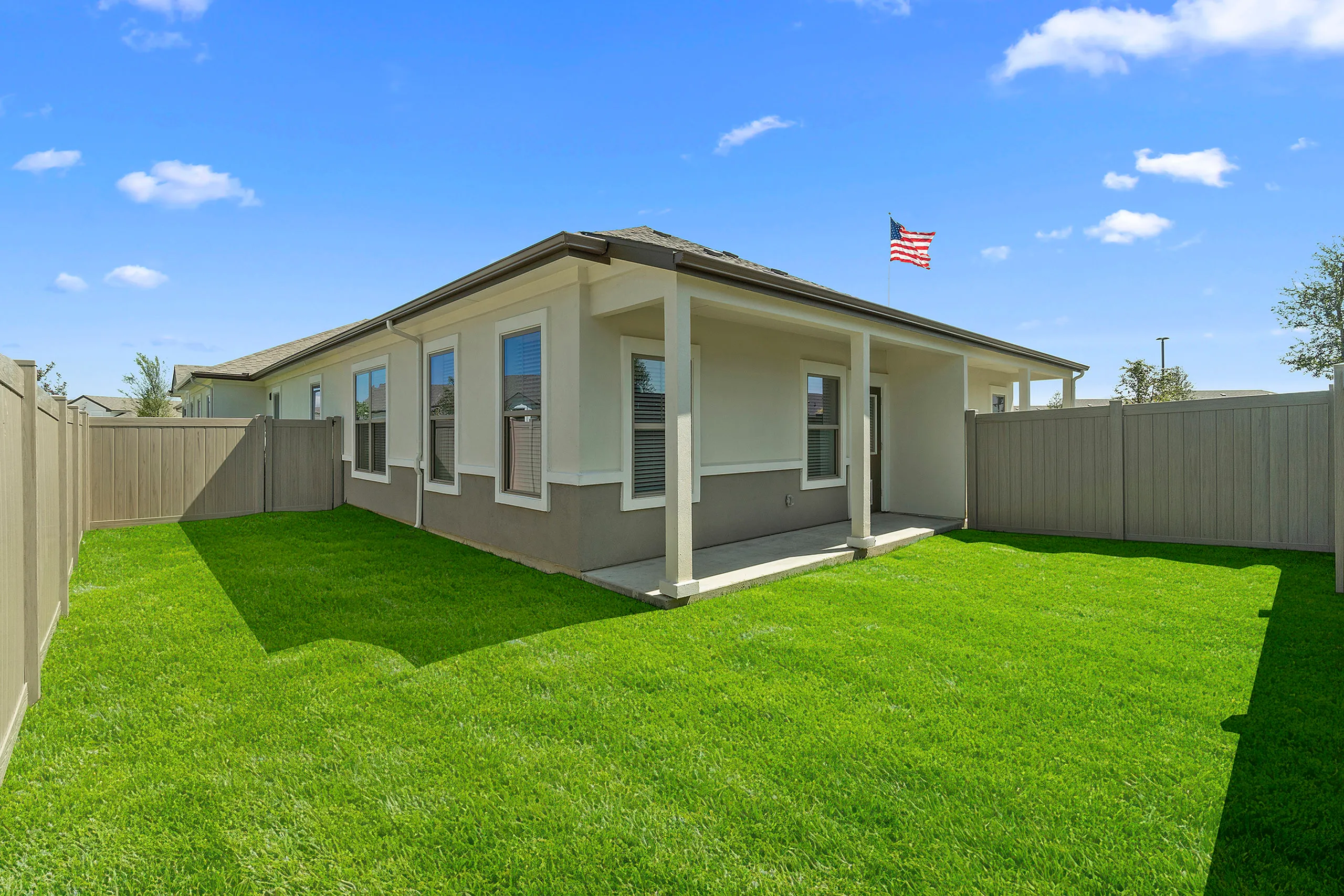 Charming backyard with lush green lawn and cozy patio, perfect for outdoor relaxation.