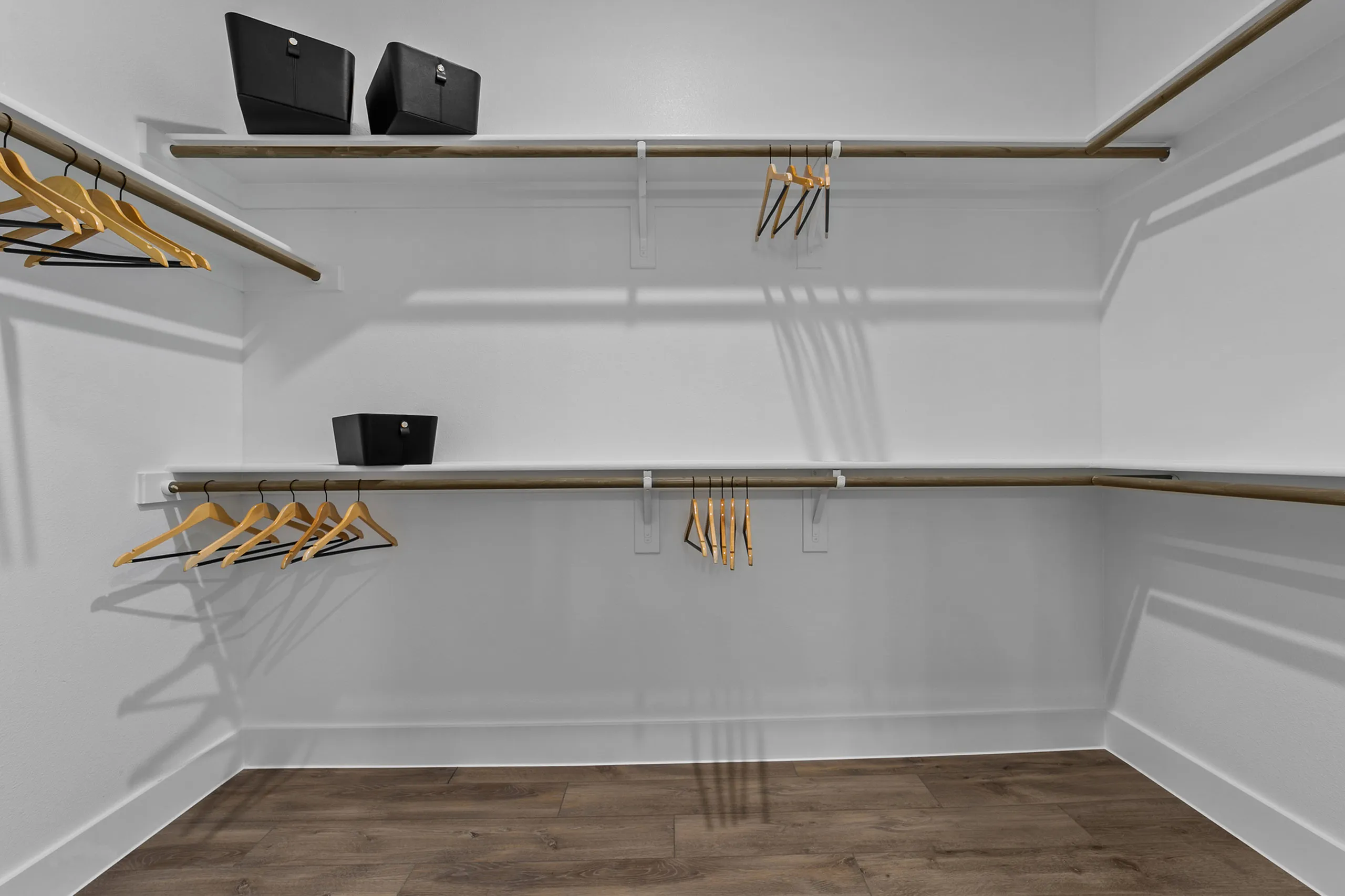 Spacious walk-in closet with elegant wooden flooring and ample hanging storage.