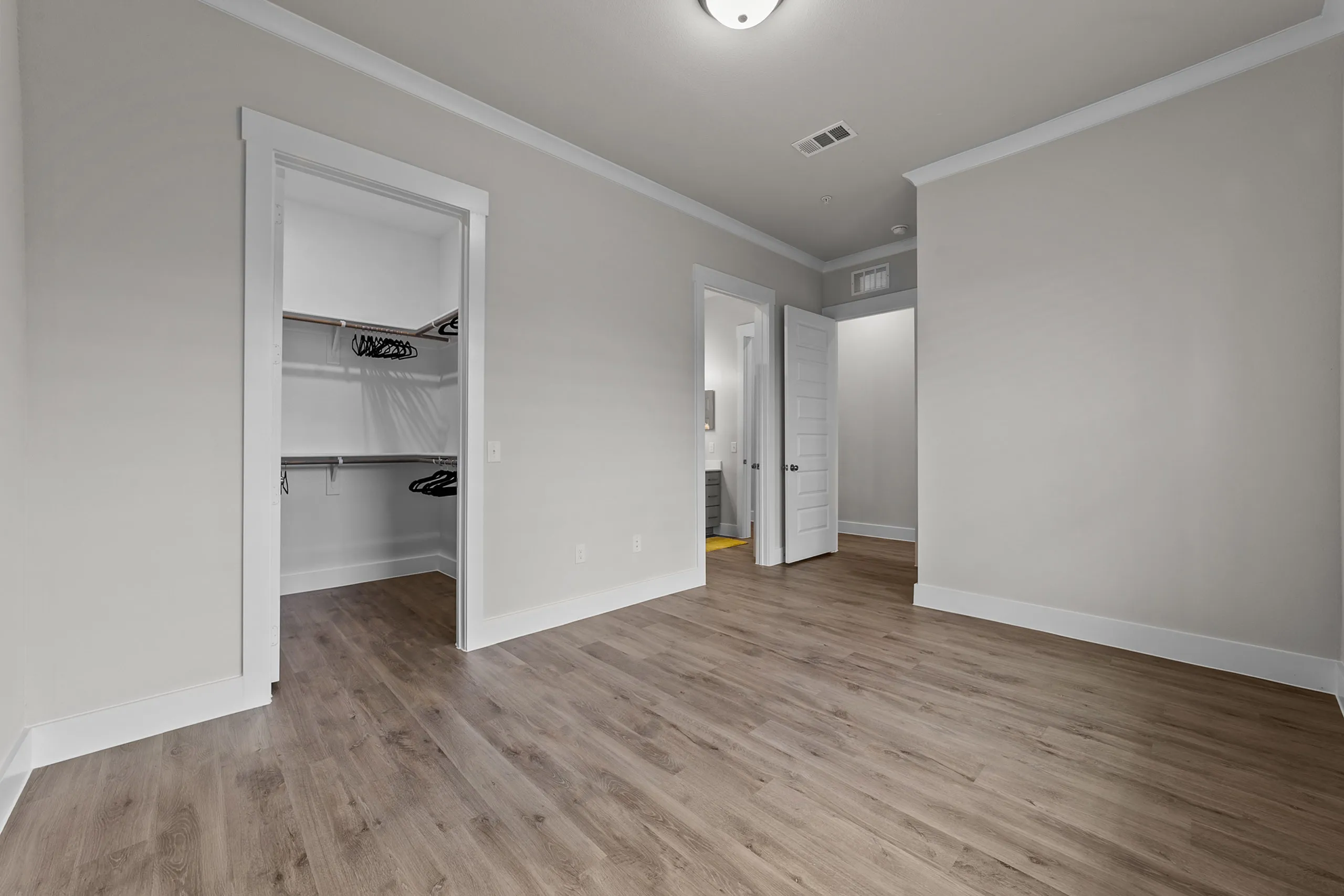 Bright and spacious bedroom with elegant hardwood flooring and a walk-in closet, perfect for a modern living space.