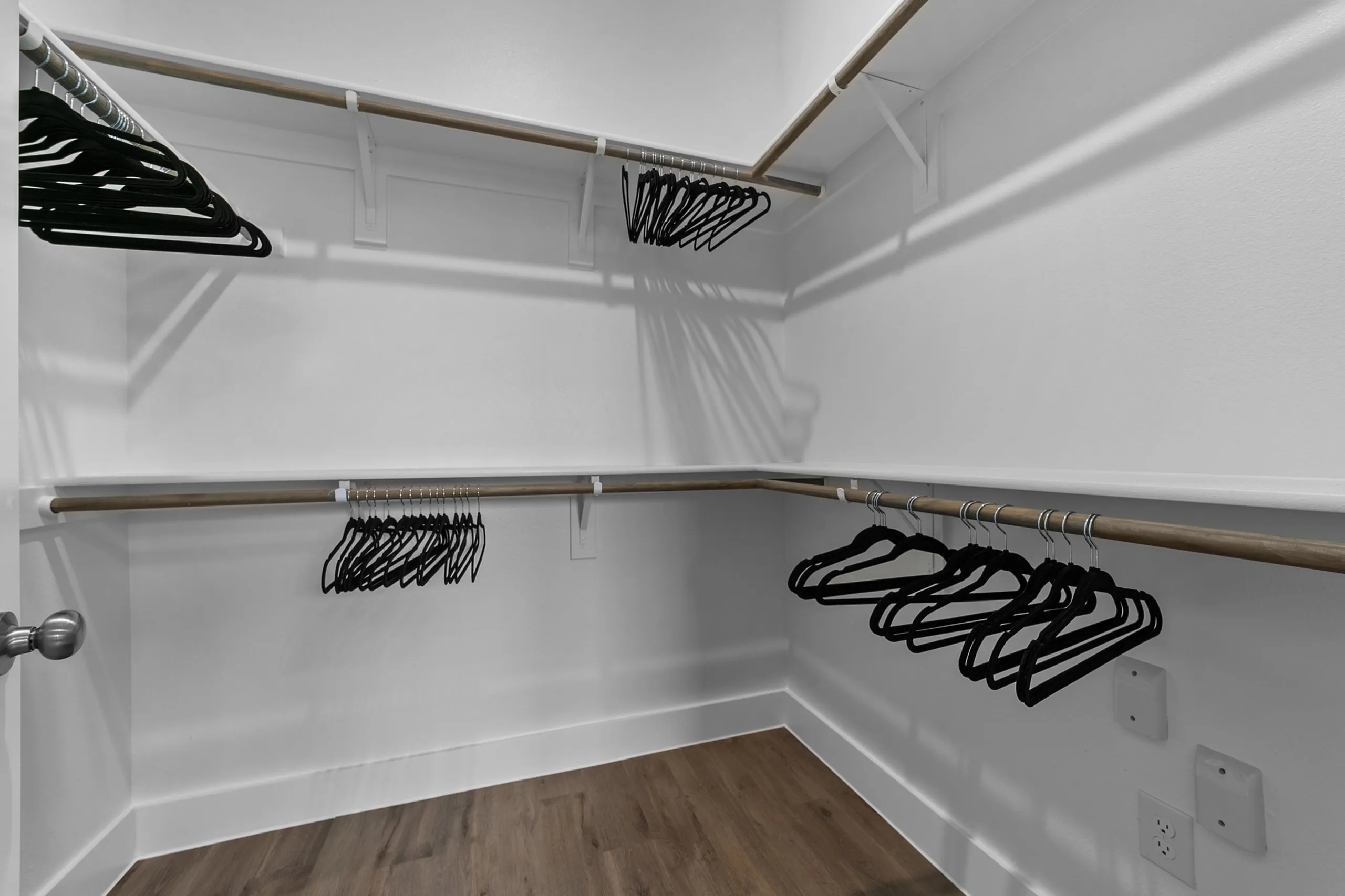 Spacious walk-in closet featuring sleek wooden hangers and elegant laminate flooring.