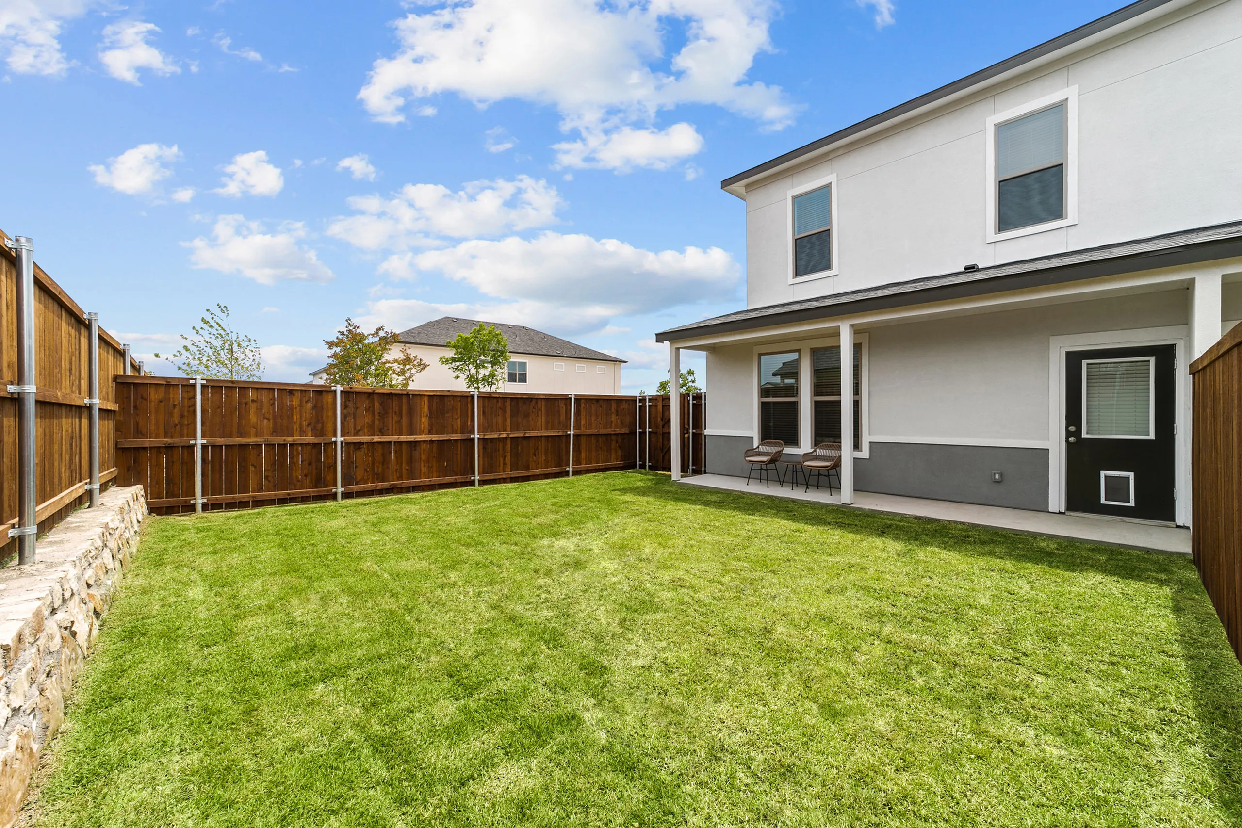 Inviting backyard with lush green lawn and cozy patio chairs, perfect for relaxation and outdoor enjoyment.