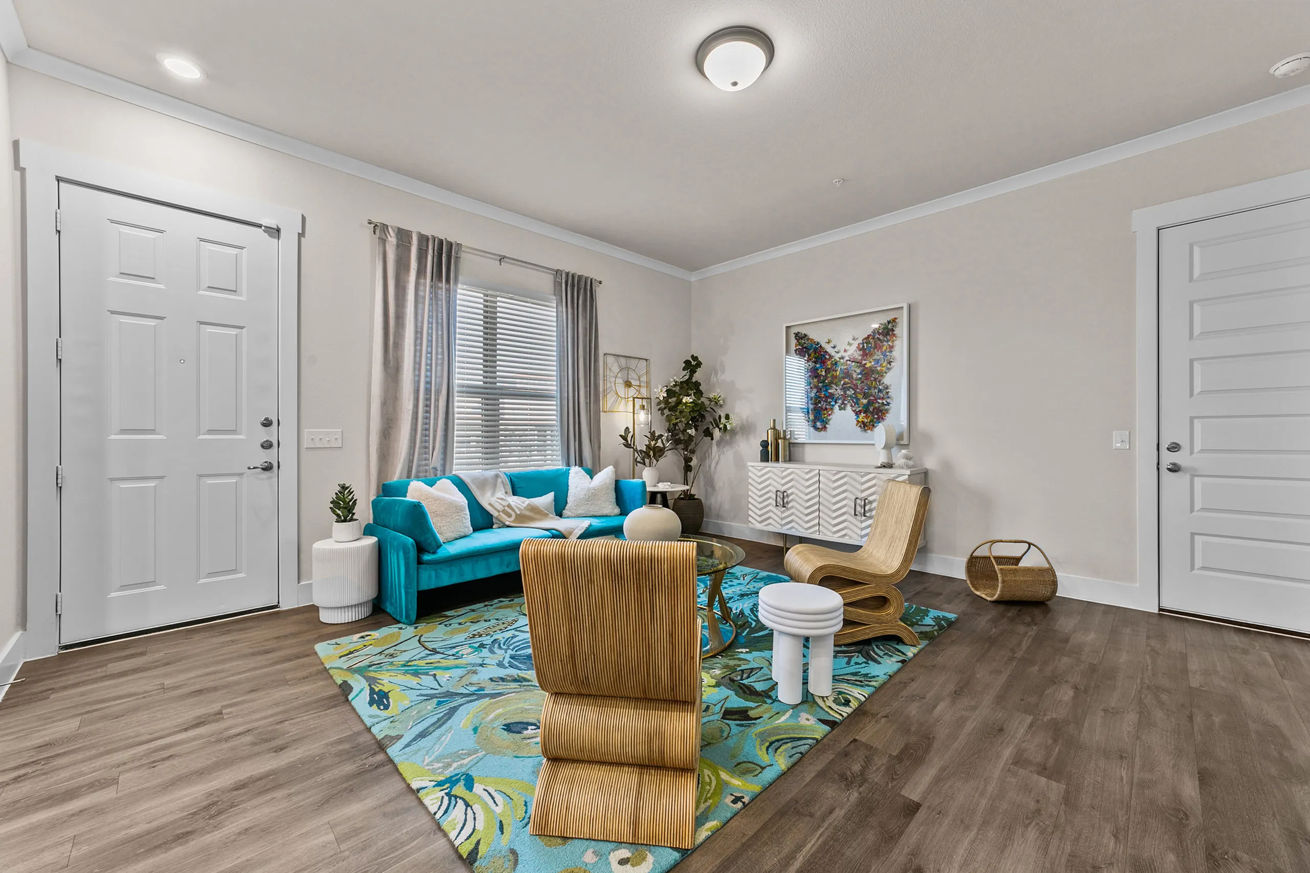 Chic living room with a vibrant turquoise couch, stylish modern chairs, and artistic decor on a colorful floral rug.