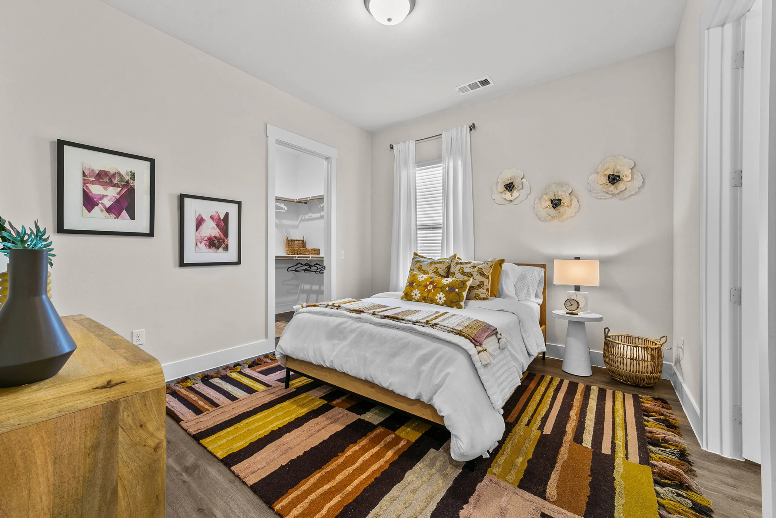 Inviting bedroom with colorful rug, elegant wall art, and cozy decor, blending comfort and style seamlessly.
