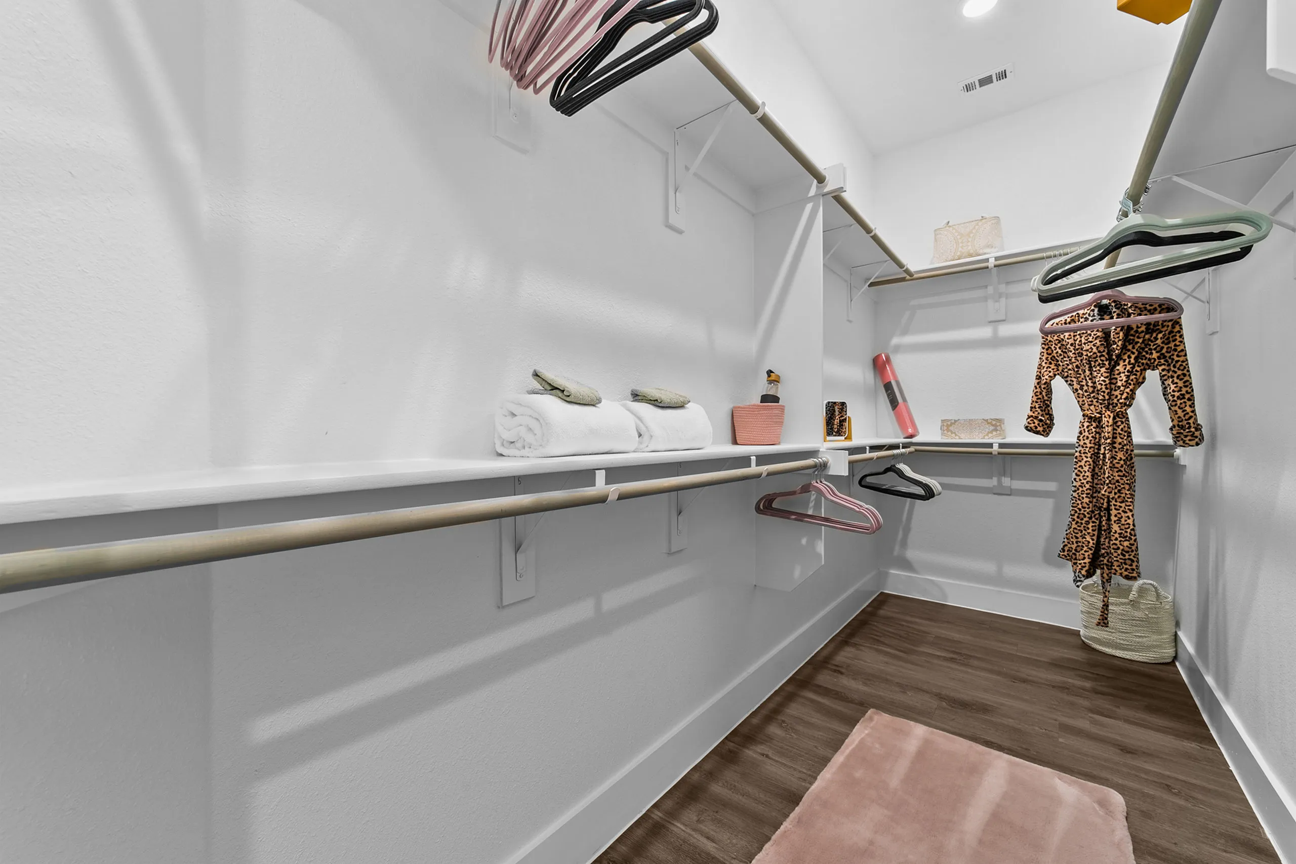 Spacious walk-in closet with modern shelving, wooden flooring, and ample storage space.