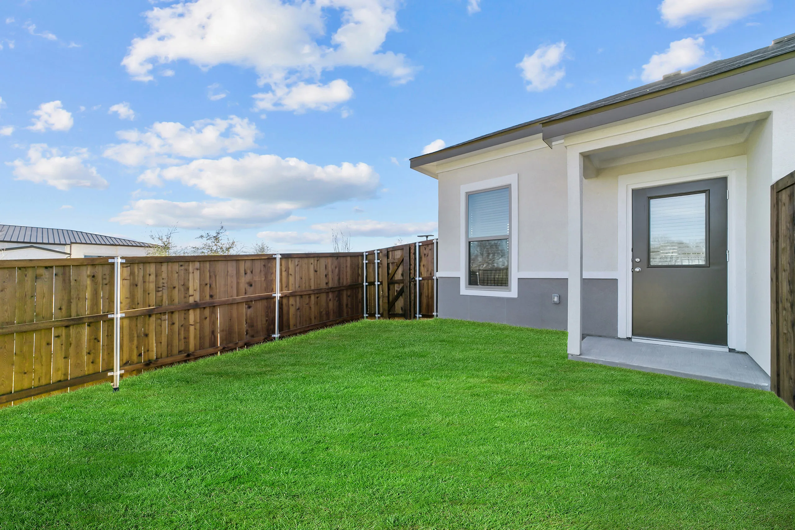 Charming backyard with lush green lawn and sleek modern door, perfect for outdoor activities and relaxation.