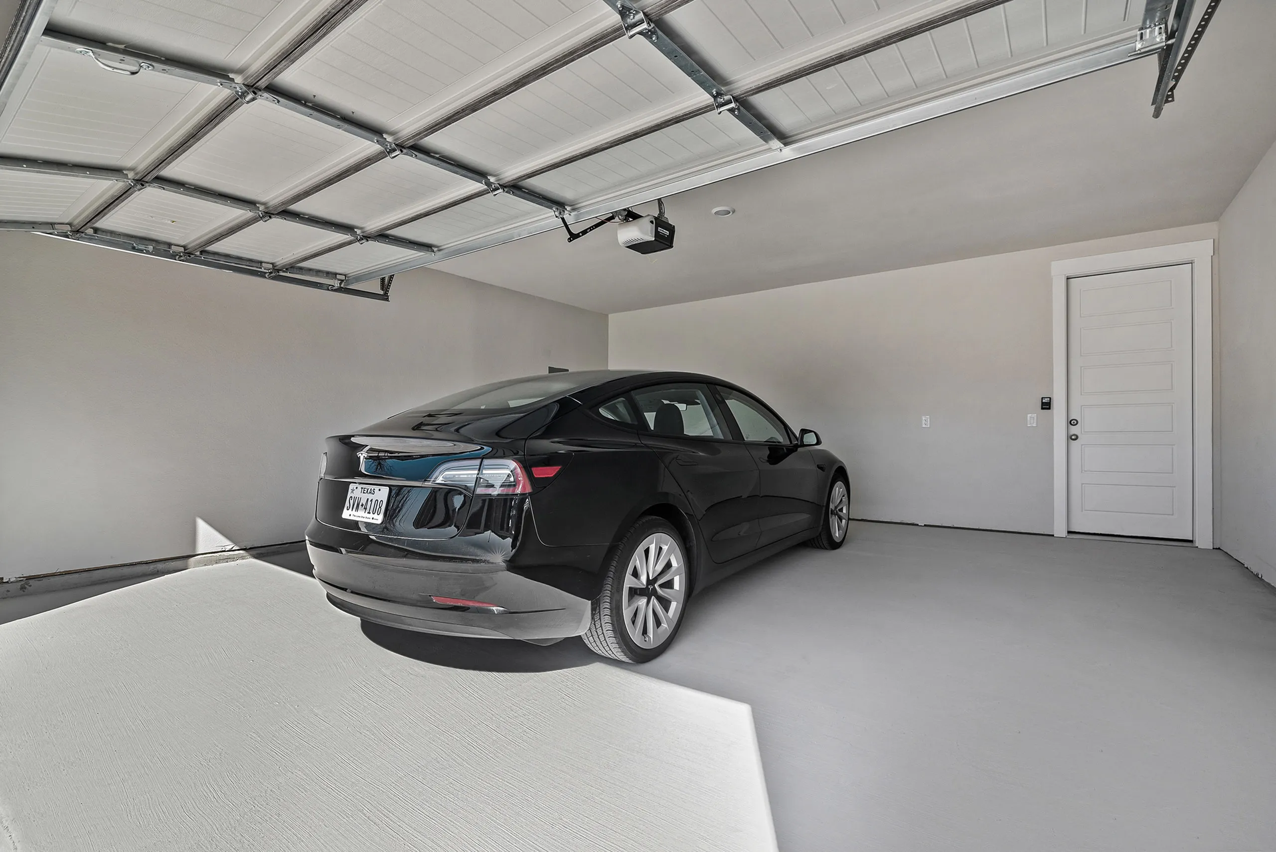 Modern garage with sleek black car, spacious interior, and high ceiling, featuring a contemporary design.