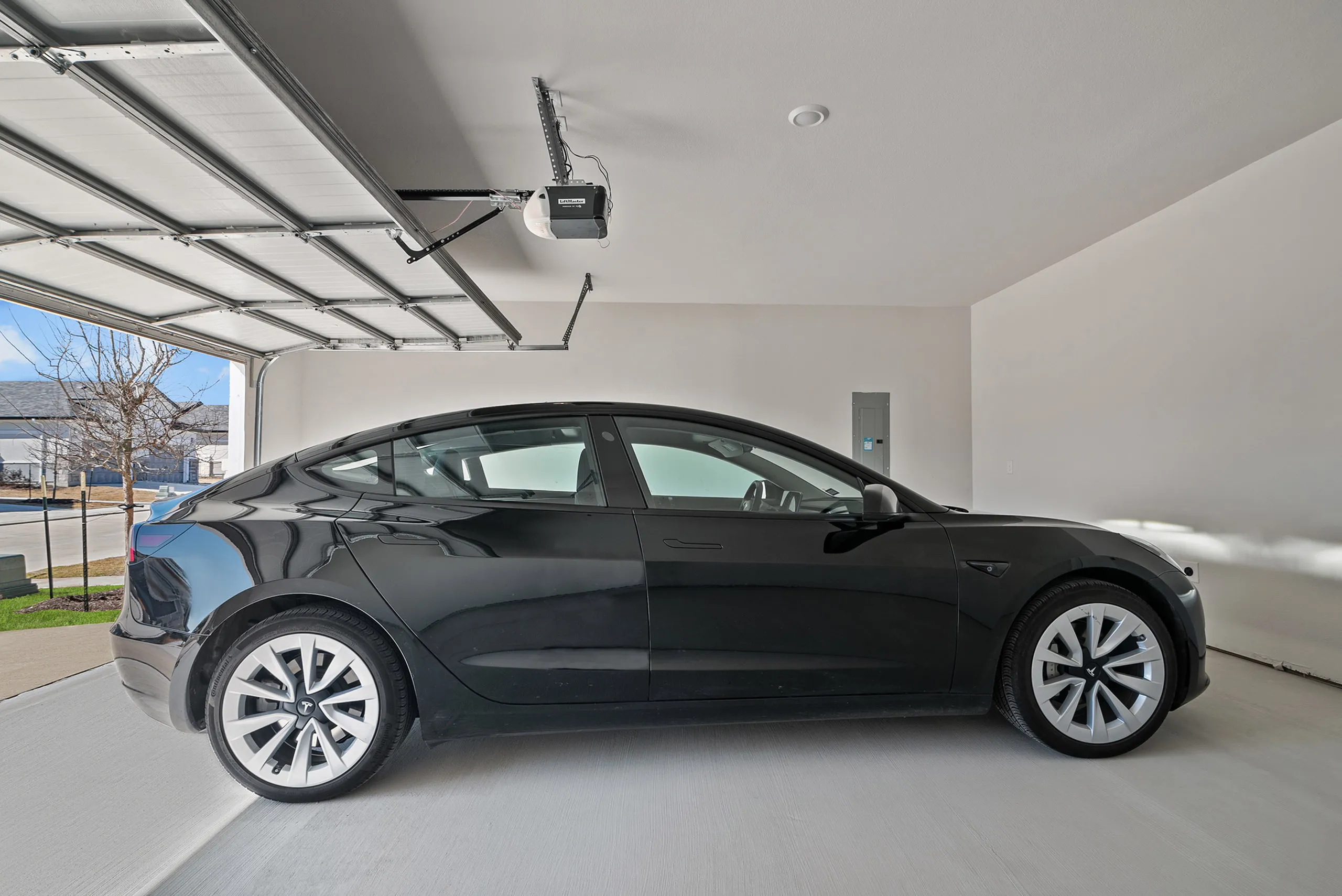 Modern garage with sleek black car parked inside, showcasing ample space and advanced automatic door opener.