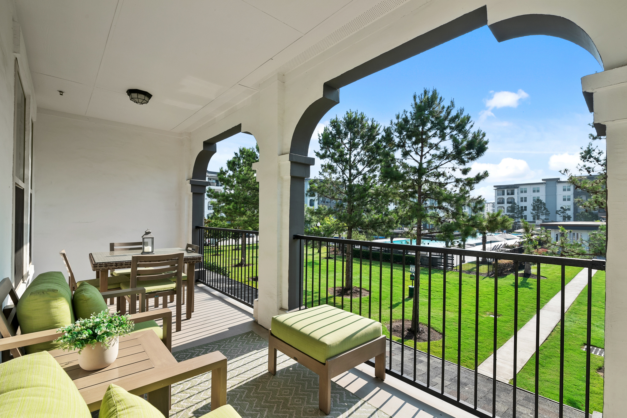 Inviting balcony with stylish green furniture overlooking lush landscaped gardens and modern architecture.