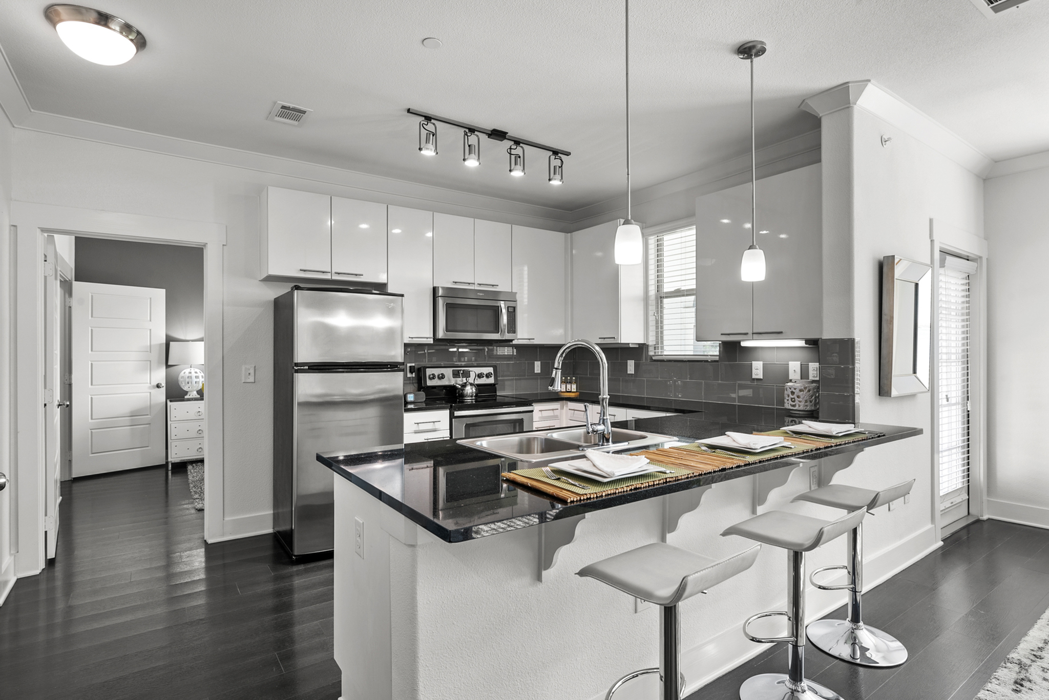 Modern kitchen with sleek black countertops, stainless steel appliances, and elegant pendant lighting, perfect for entertaining.