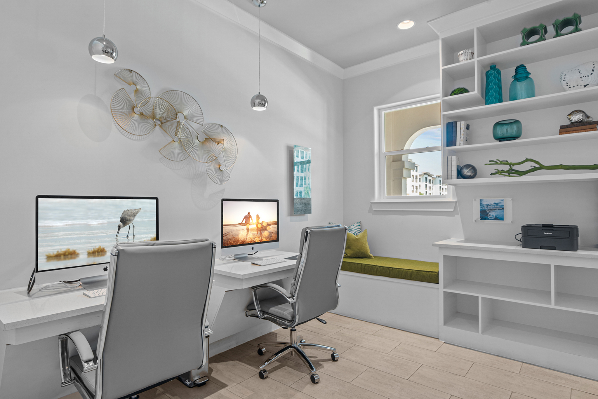Bright home office featuring sleek white desks, modern decor, and a cozy window seat with a built-in shelf.