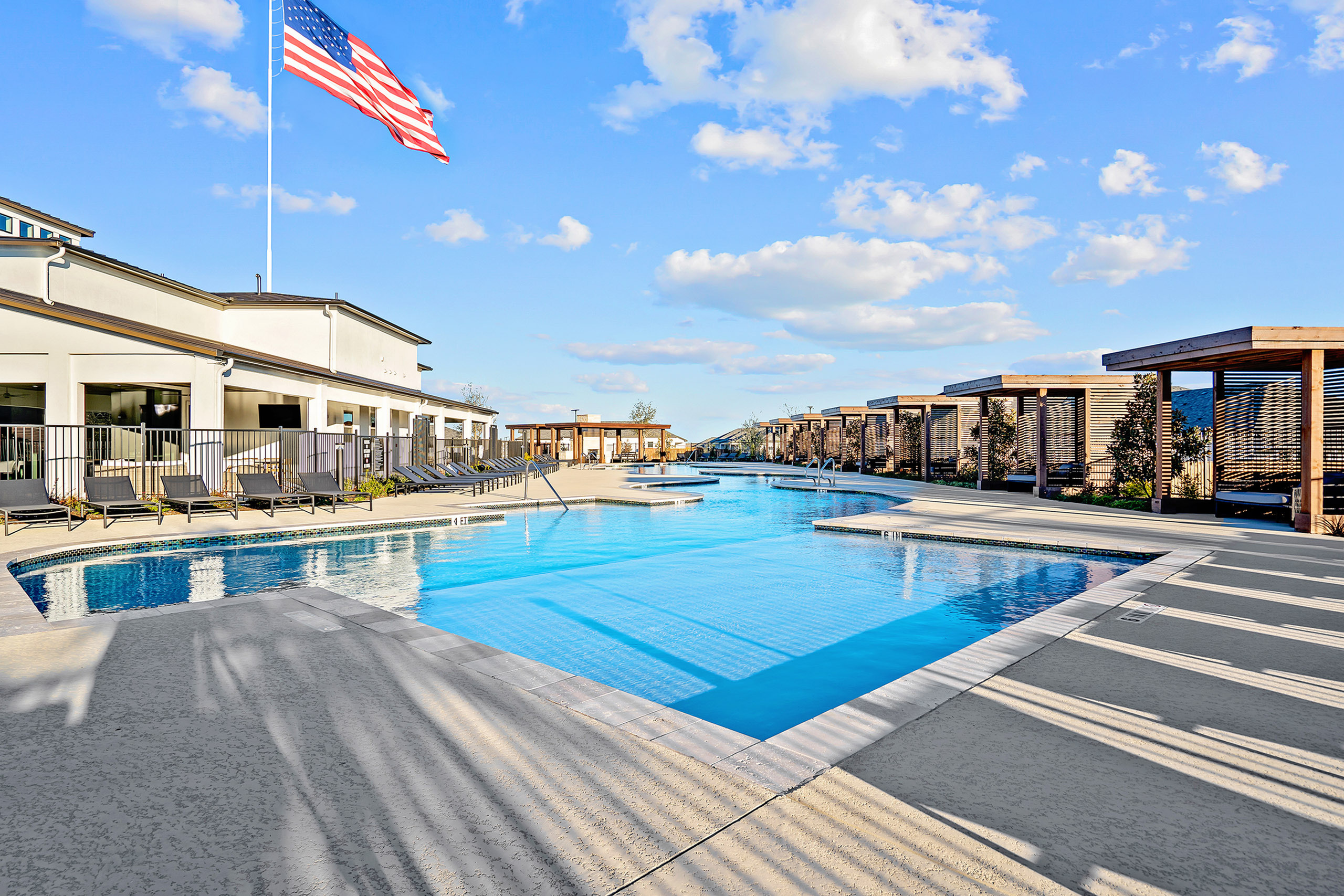 Luxurious poolside area with sleek lounge chairs, stylish pergolas, and a clear blue sky backdrop.