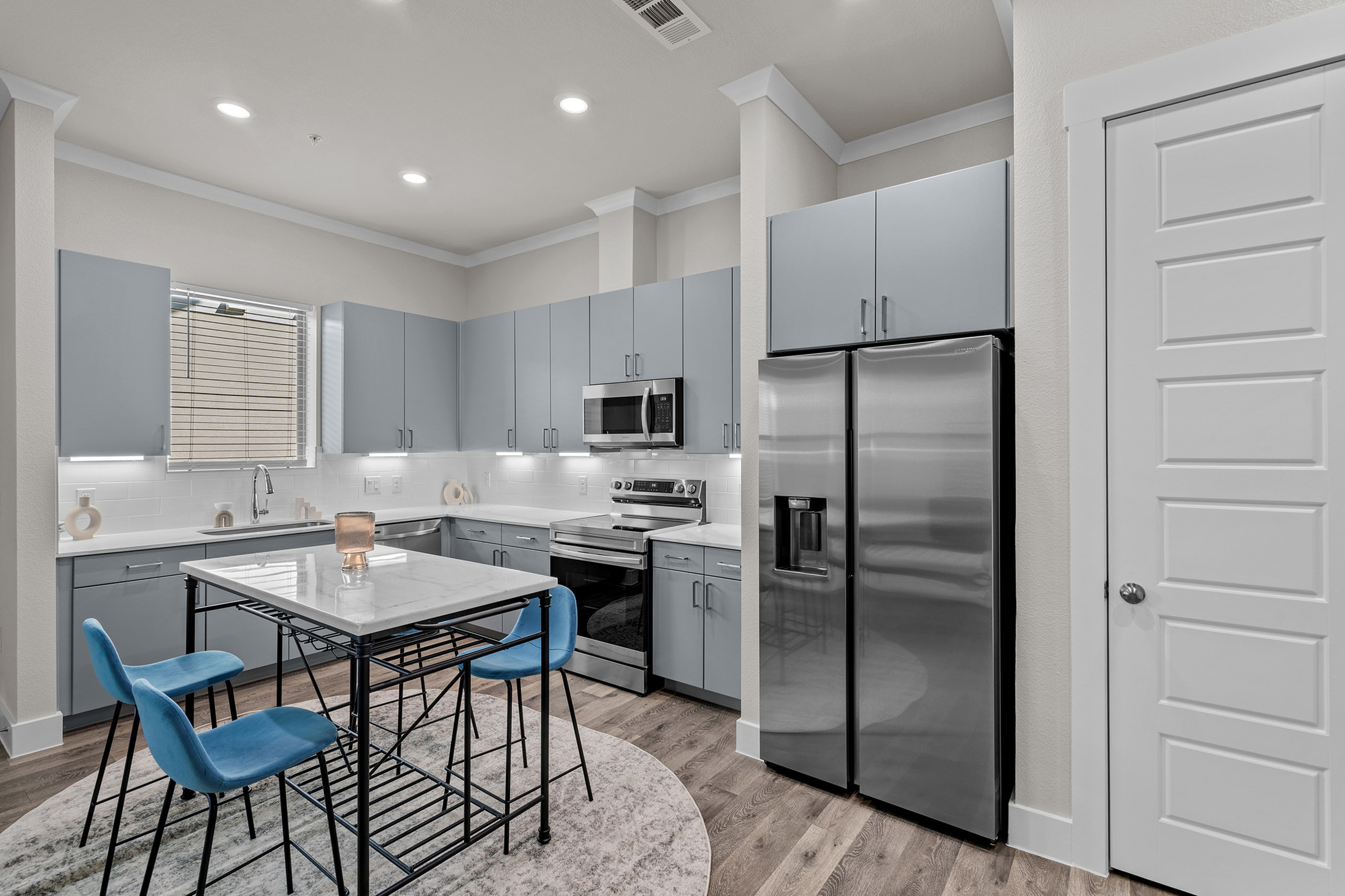 Contemporary kitchen with sleek blue cabinets, stainless steel appliances, and chic dining space.