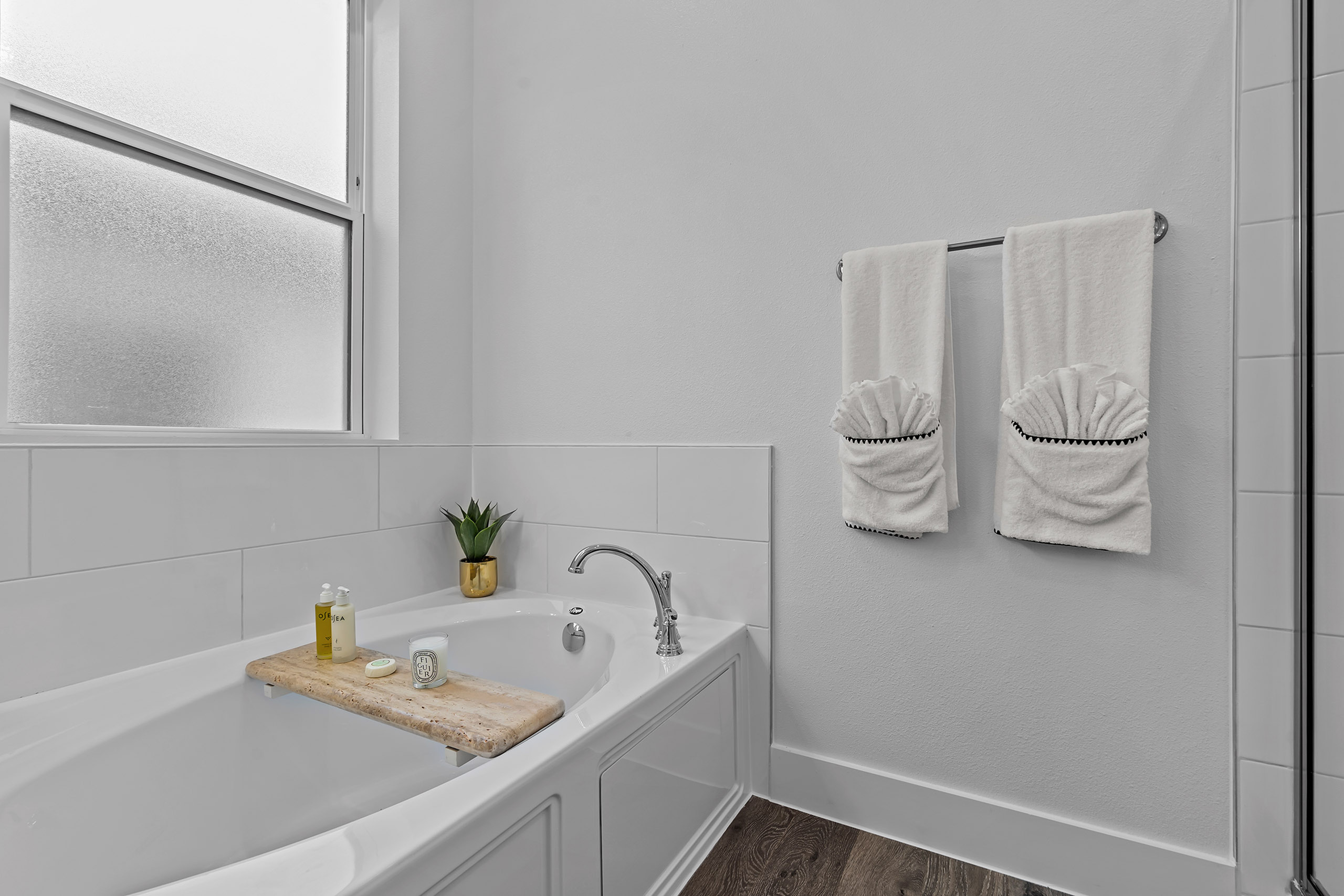 Contemporary bathroom featuring a sleek bathtub with luxury amenities and elegant towel display.