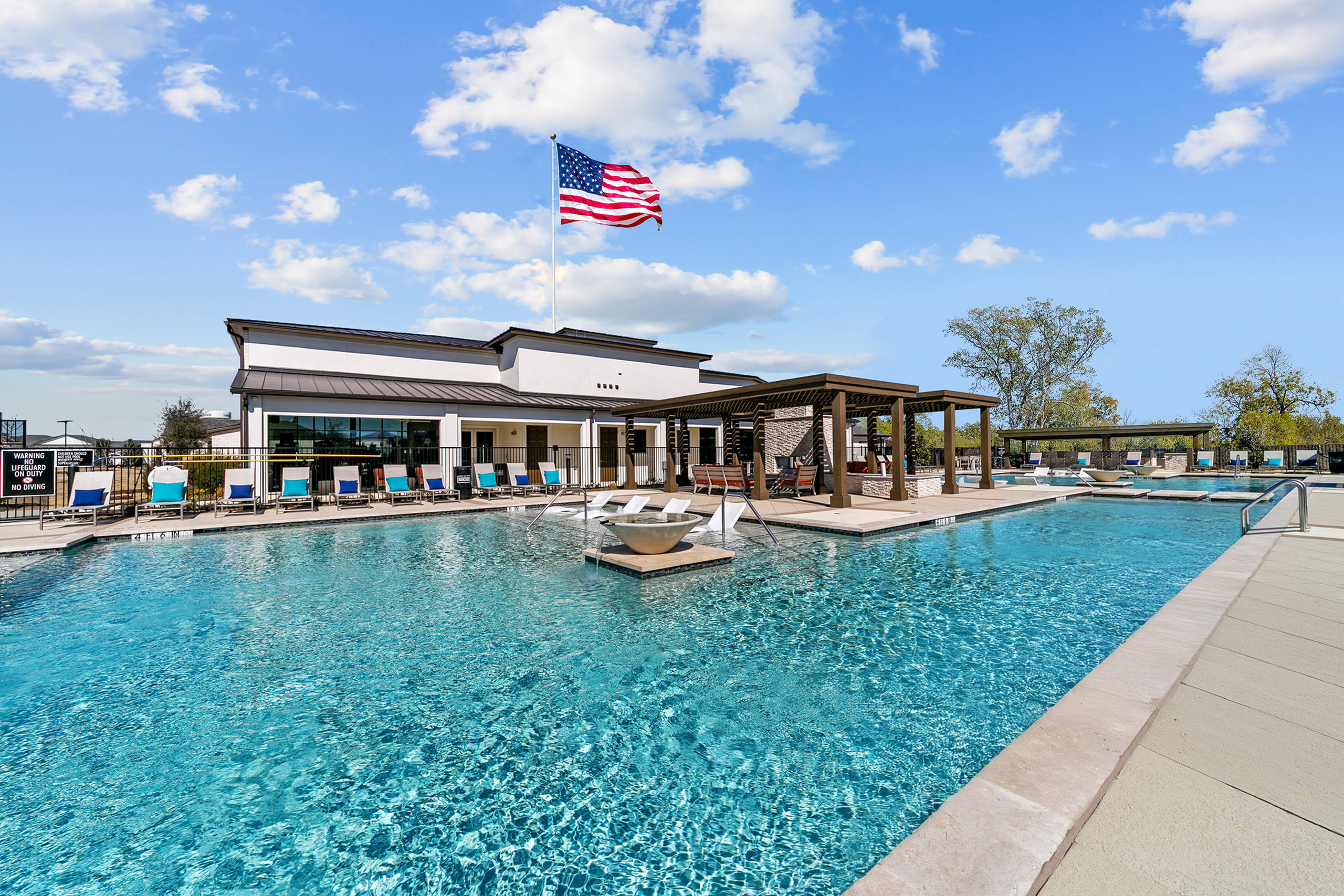 Inviting apartment community pool with crystal-clear water, sun loungers, a pergola, and vibrant outdoor seating.