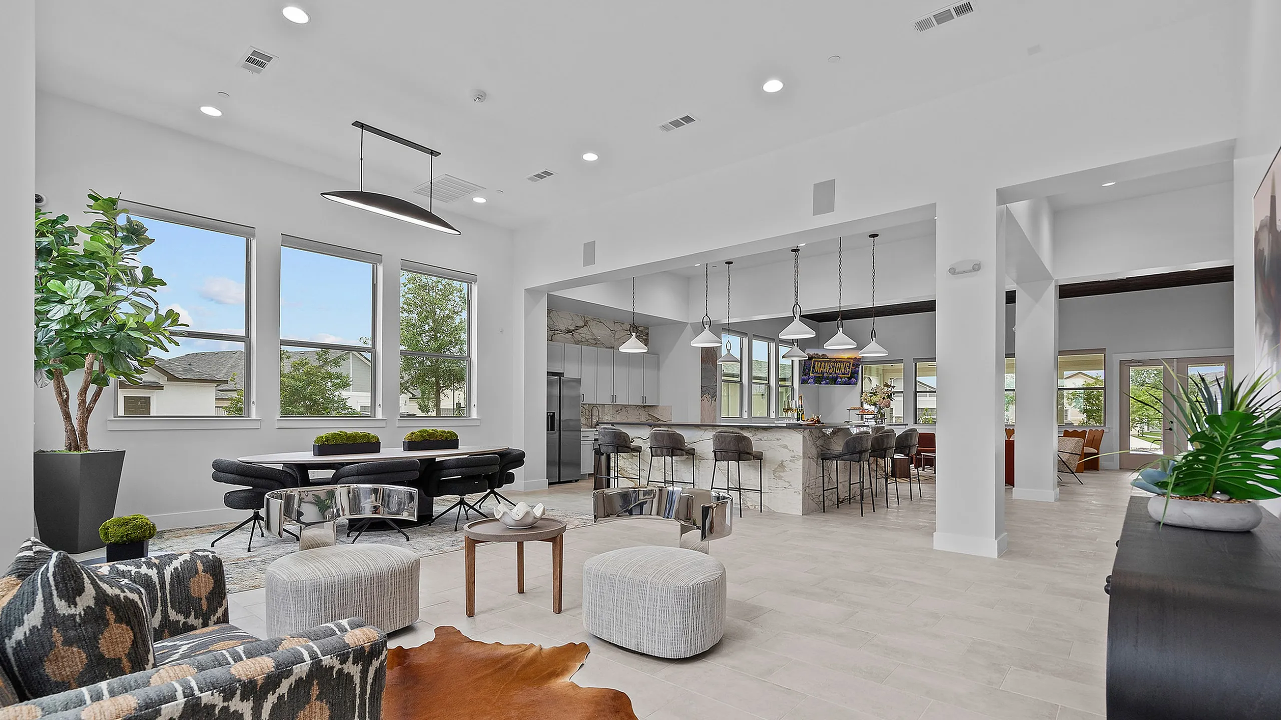 Luxurious clubhouse space featuring modern furniture, natural light from large windows, and a stylish kitchen with a marble island.
