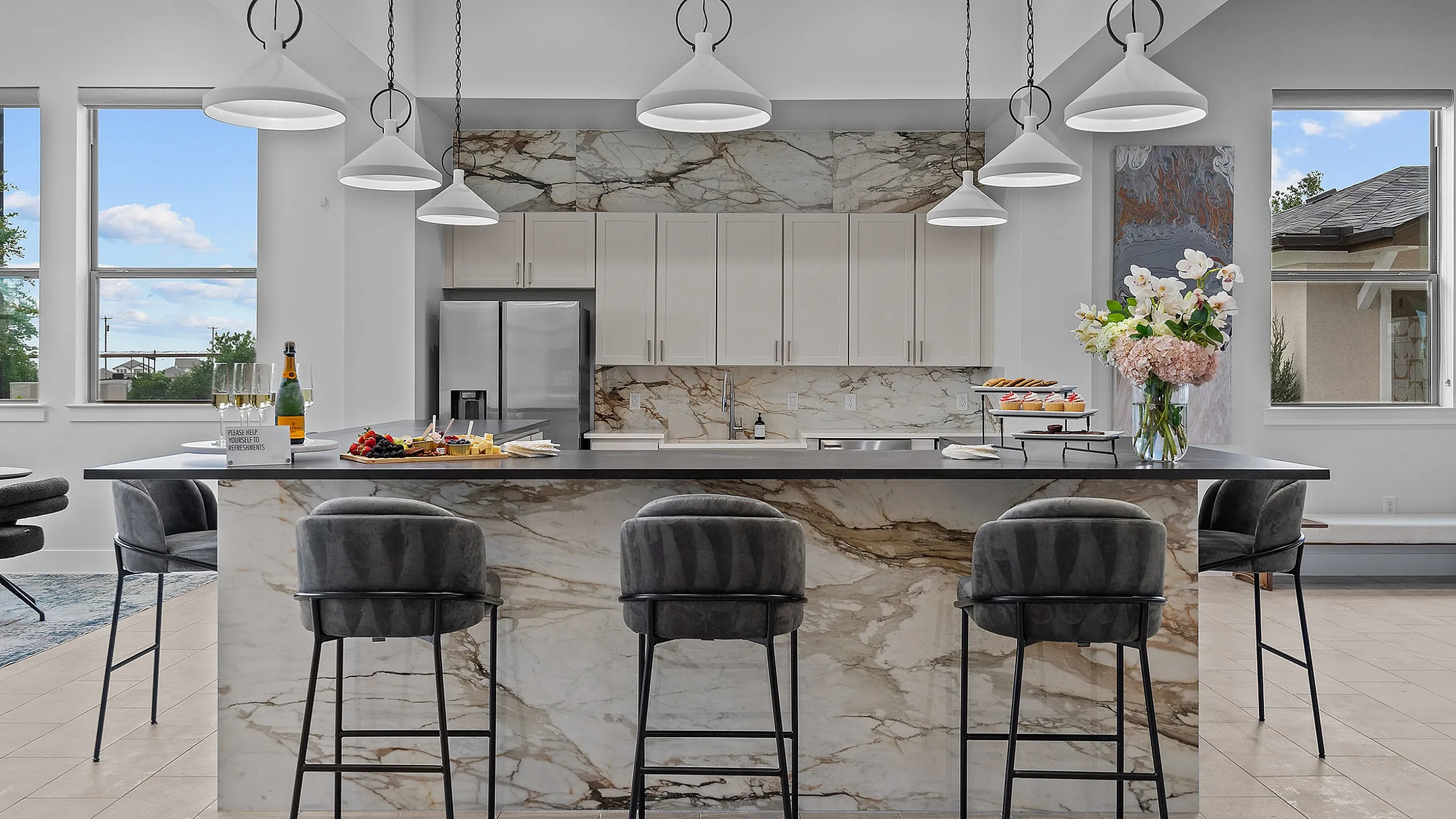 Elegant modern kitchen with marble countertops, sleek pendant lighting, and stylish bar stools, perfect for entertaining.