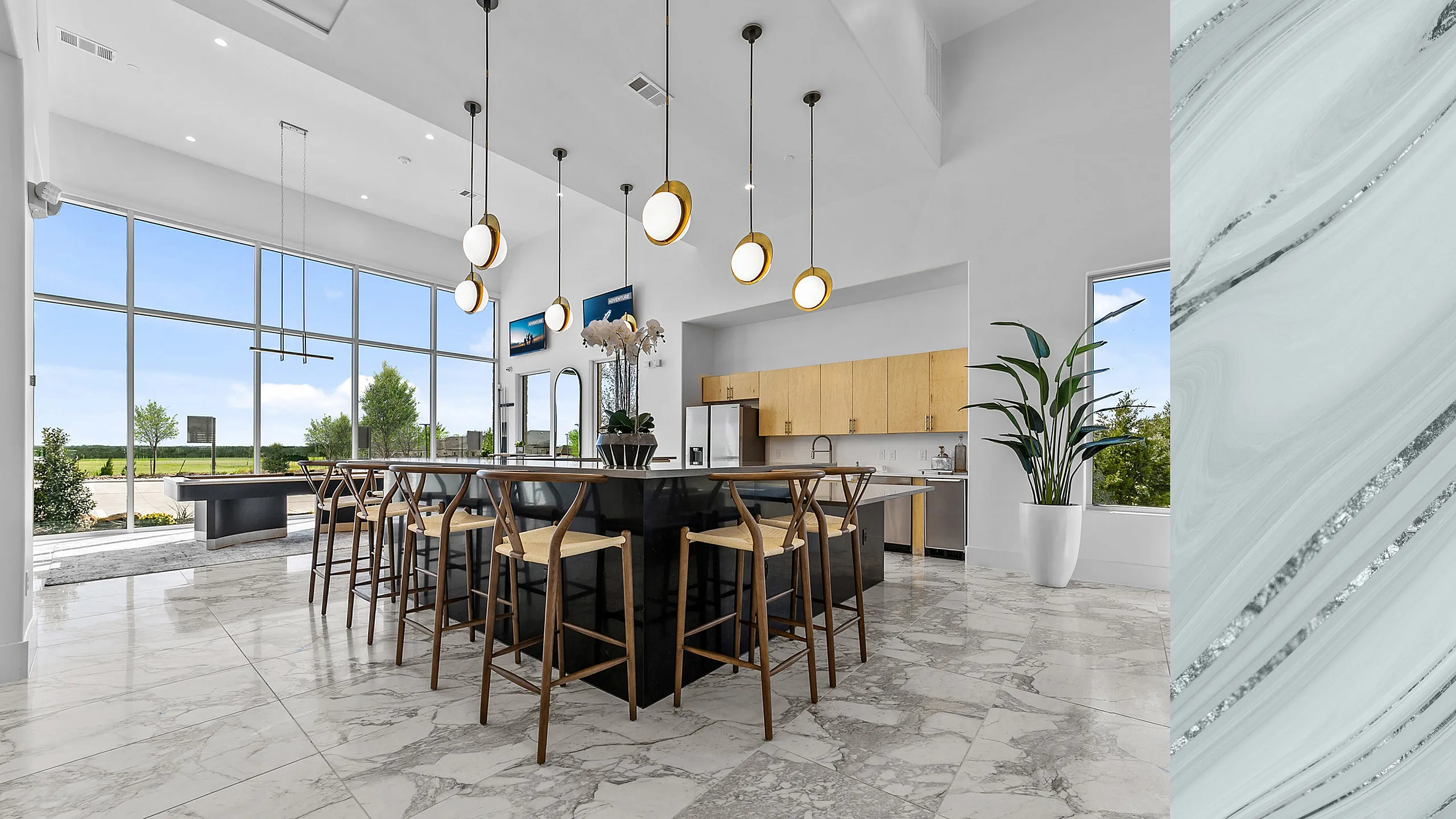 Luxurious modern kitchen with high ceilings, elegant lighting, and a spacious island with stylish seating, overlooking a panoramic outdoor view.
