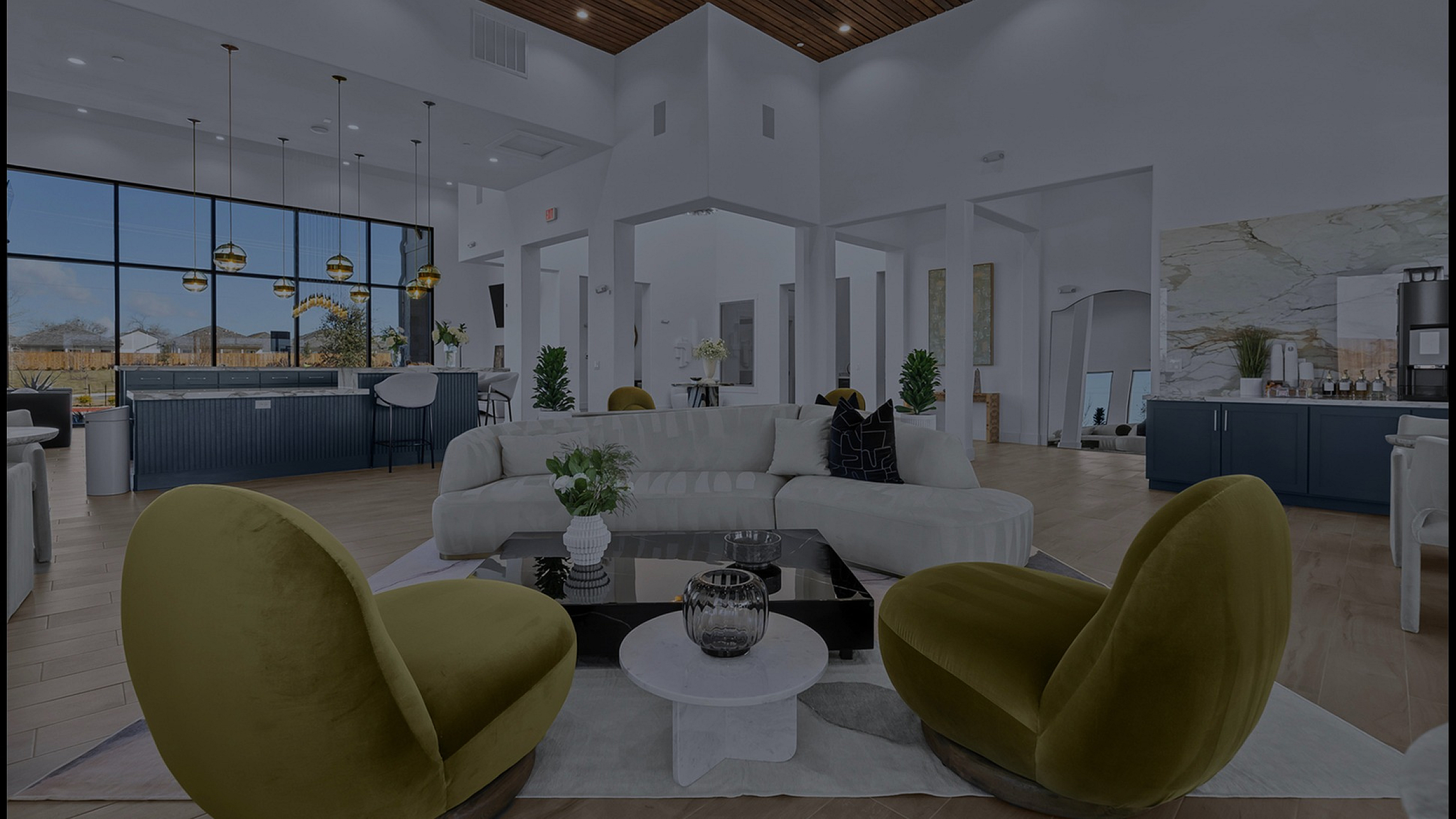 Luxurious modern living room with plush green chairs, elegant neutral sofa, and large windows overlooking a serene view.