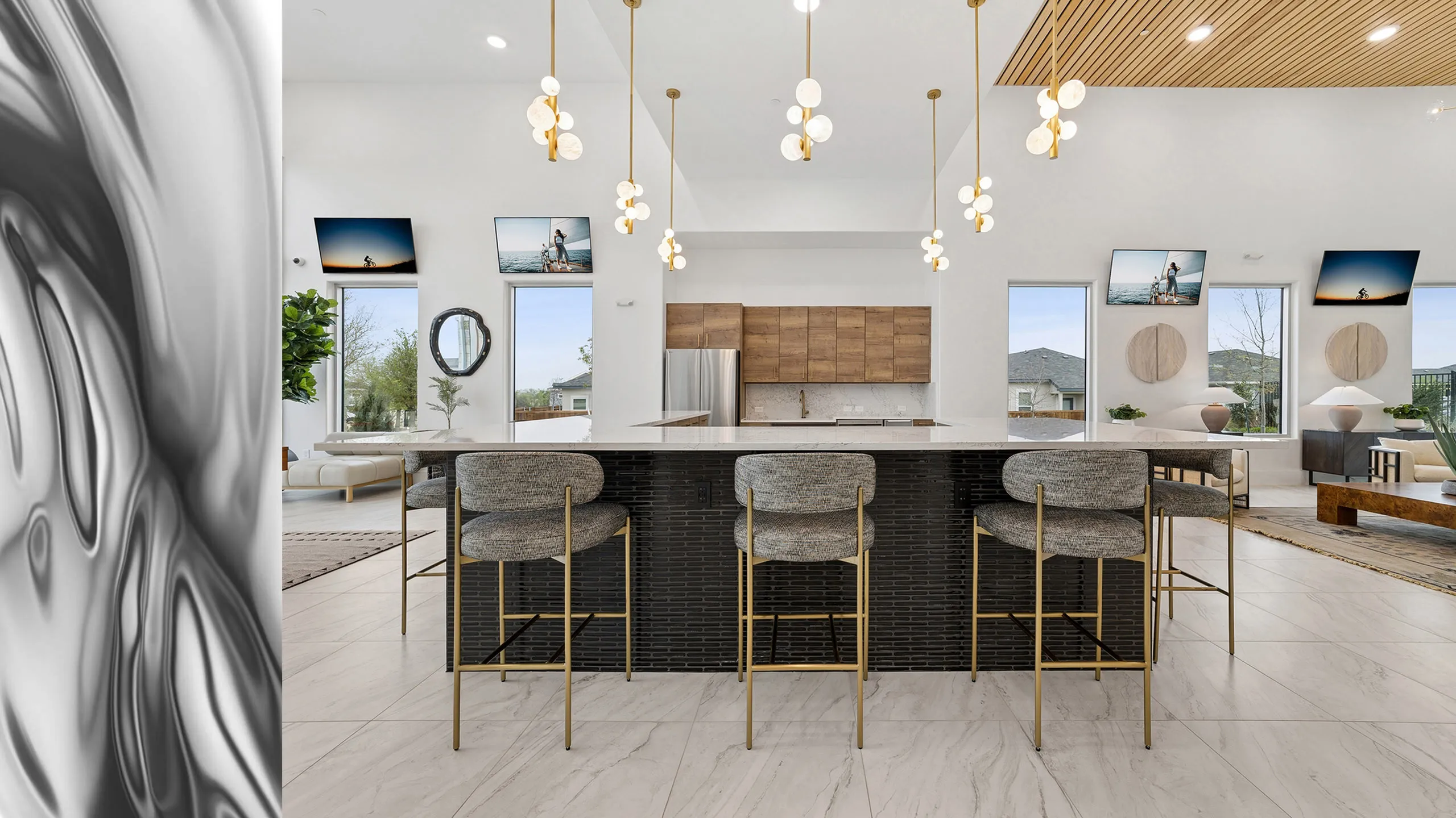 Modern kitchen with sleek pendant lights, elegant marble countertops, and stylish bar seating in a bright, open-layout living space.