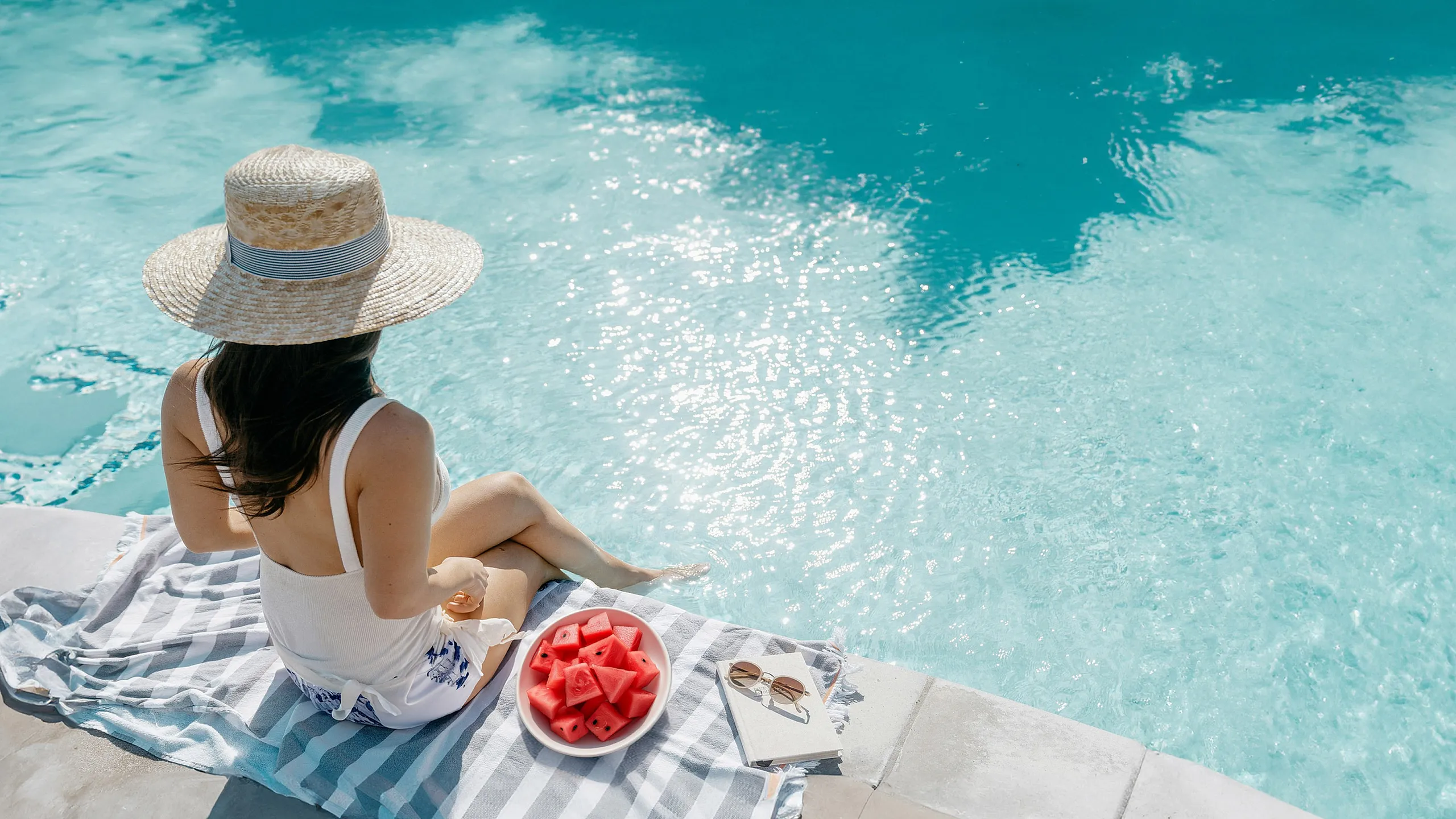 Serene poolside relaxation with refreshing watermelon slices, inviting clear water, and a cozy sunhat setting.