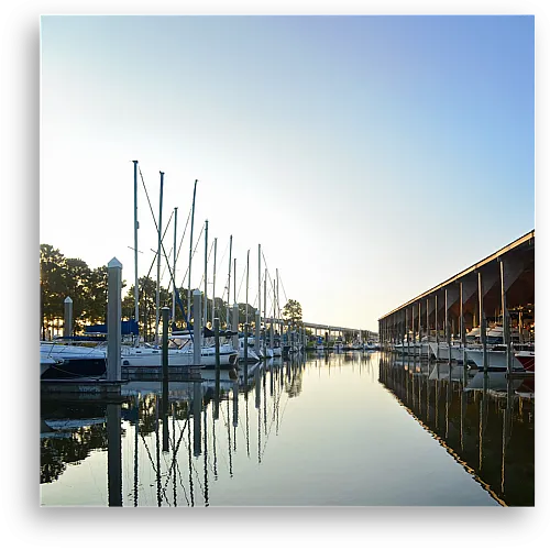 Serene marina view with sailboats and tranquil waterfront reflections at sunset, creating a relaxing maritime atmosphere.